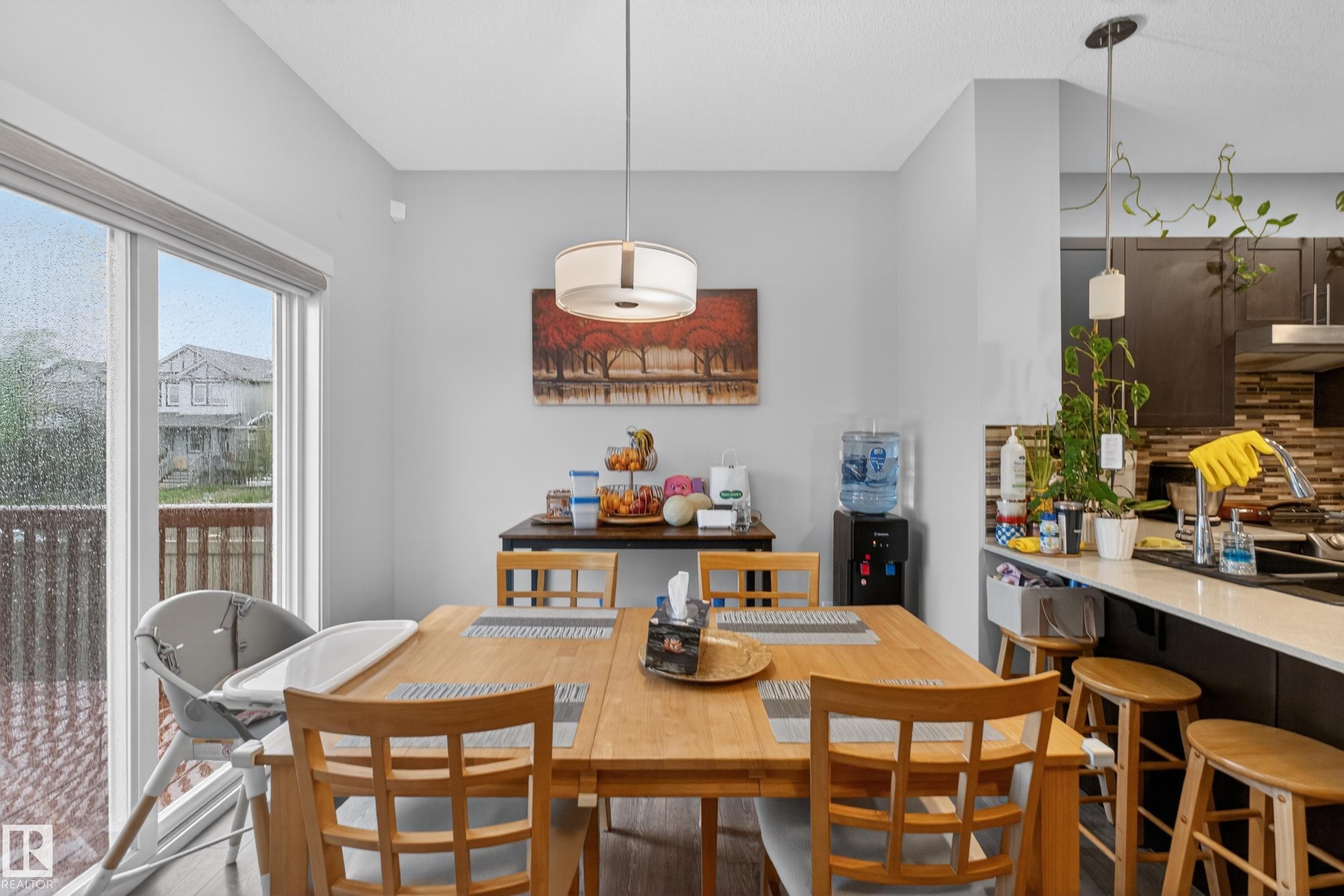 Dining area featuring wood-finish flooring, a contemporary drum pendant light, and sliding glass doors opening to a deck - 1404 25 Avenue, Edmonton, AB