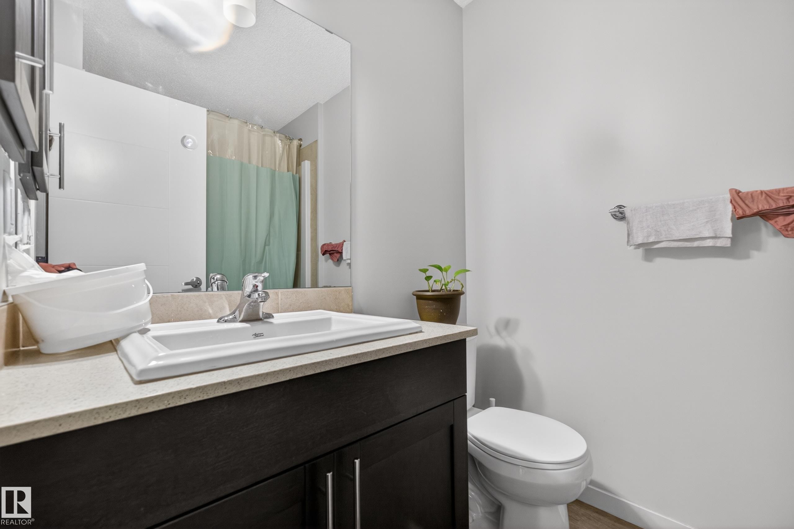 Dark wood-finish vanity with a white rectangular undermount sink, a chrome faucet, and a light-toned countertop - 1404 25 Avenue, Edmonton, AB