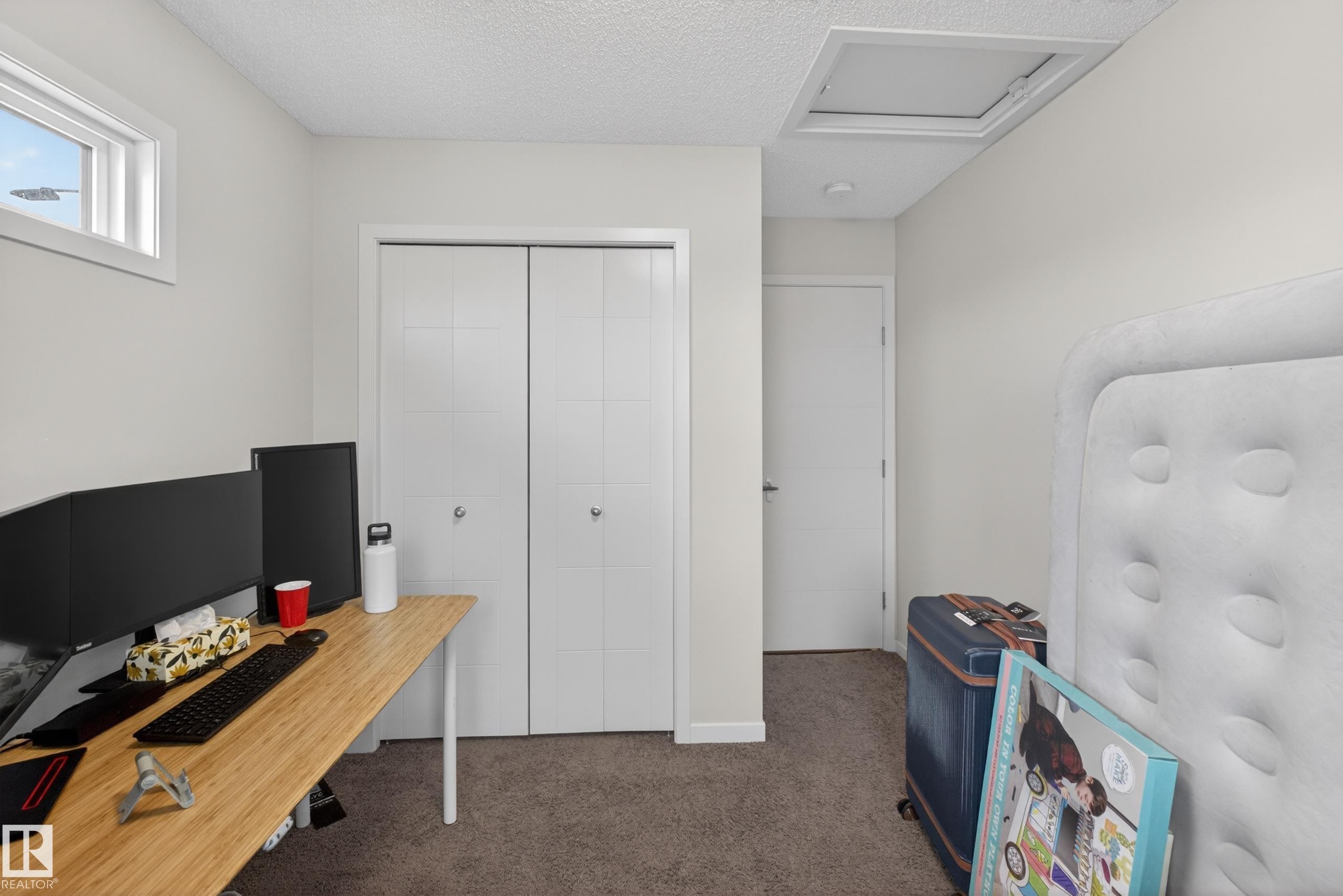 Room featuring neutral wall paint, textured ceiling, a double bi-fold closet, and a white interior door - 1404 25 Avenue, Edmonton, AB