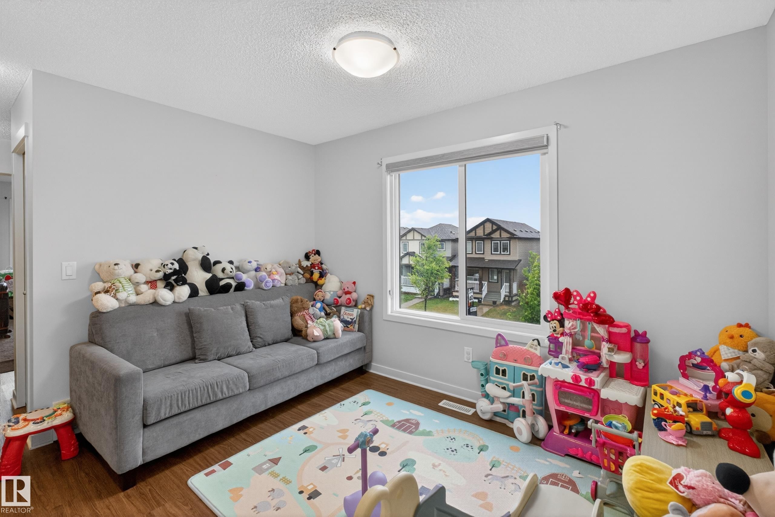 Bright interior room featuring a large window with white trim, wood-finish flooring, and light-toned walls - 1404 25 Avenue, Edmonton, AB