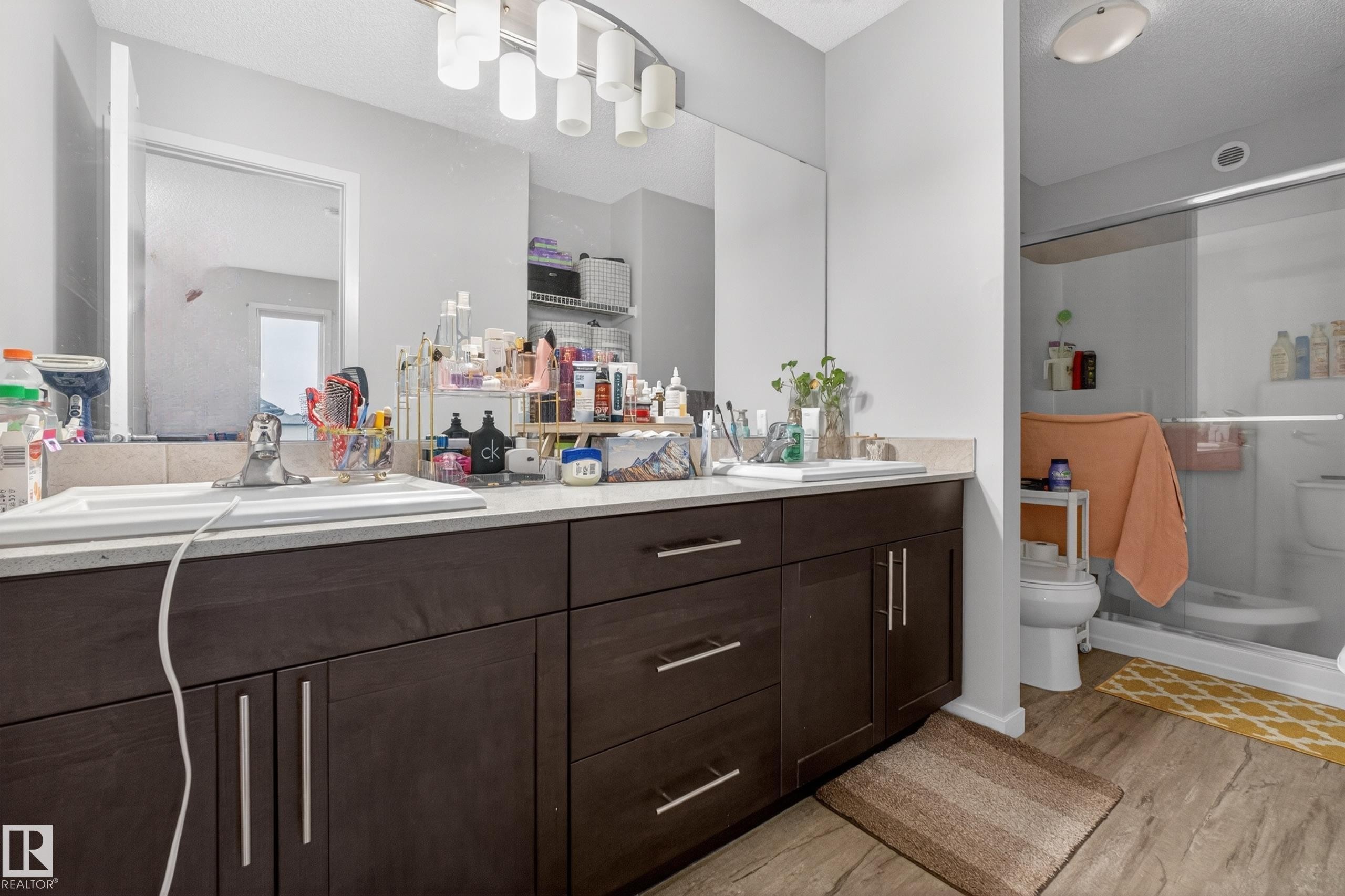 Bathroom featuring a double vanity with dark wood-finish cabinetry, light-toned countertop, and dual sinks - 1404 25 Avenue, Edmonton, AB