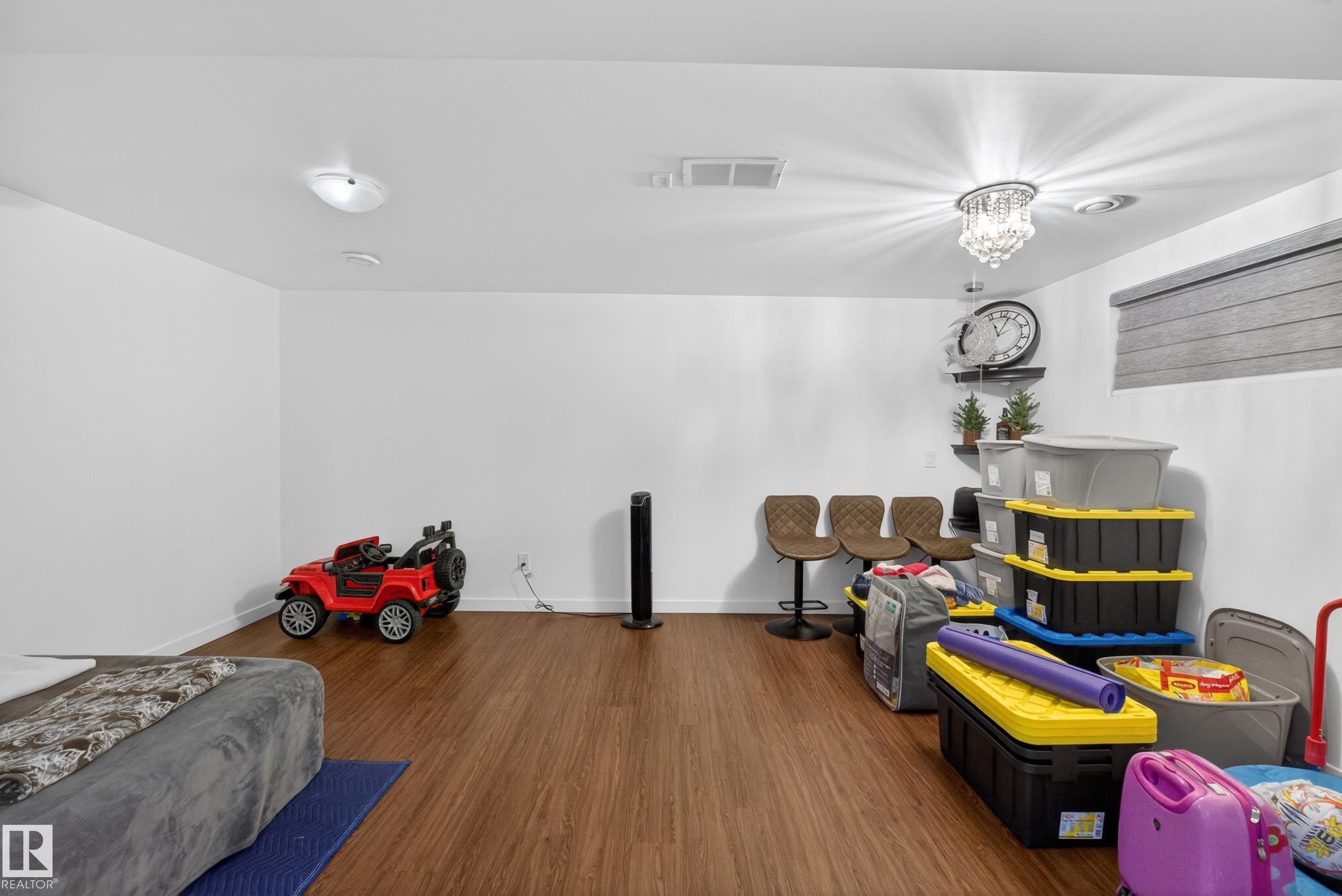 Room featuring wood-finish flooring, white walls, and a decorative ceiling light fixture - 1404 25 Avenue, Edmonton, AB