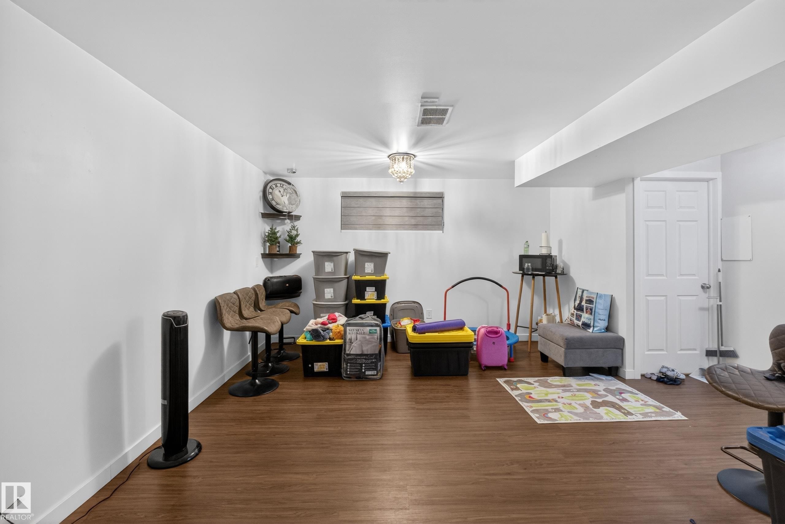 Spacious room featuring wood-finish flooring, white walls, recessed lighting, and a six-panel door - 1404 25 Avenue, Edmonton, AB