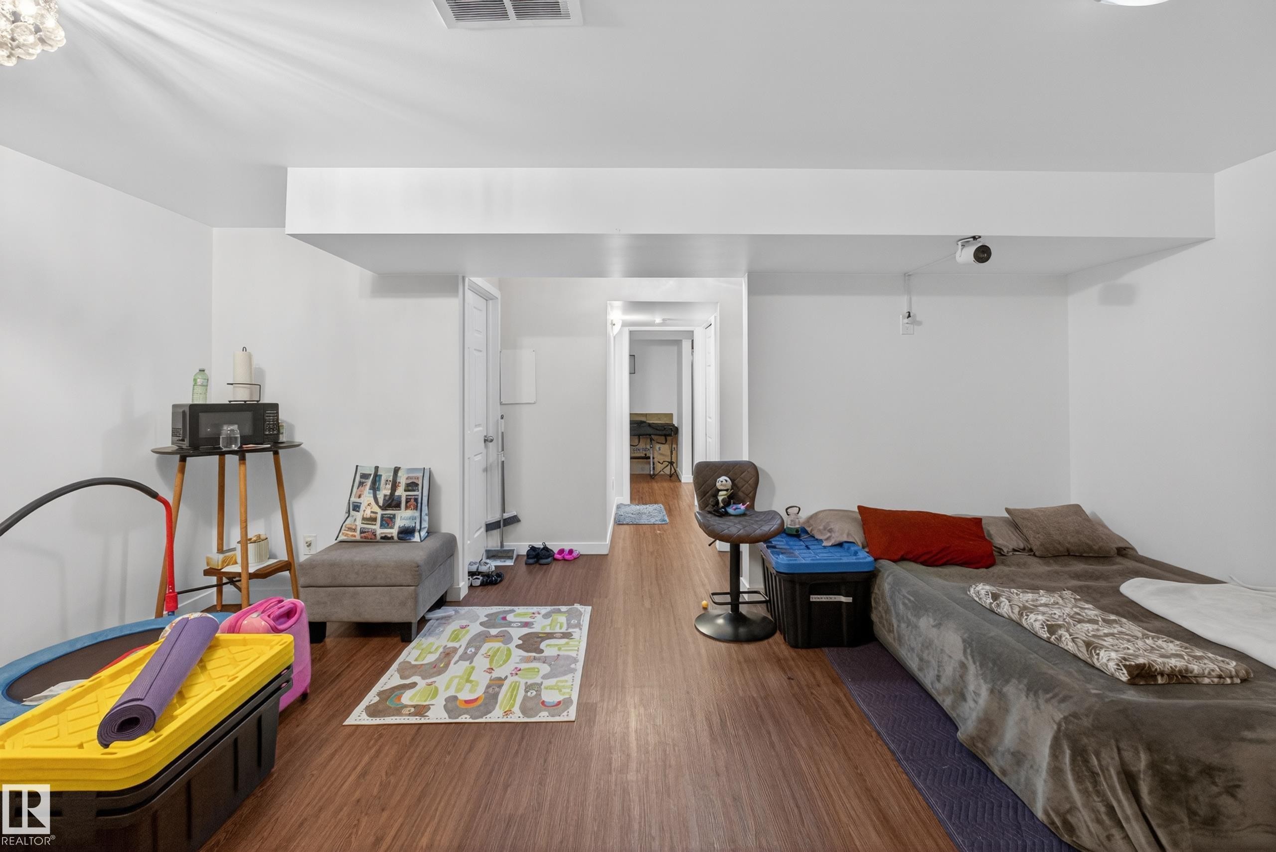 Spacious room featuring wood-finish flooring, white walls, and recessed lighting - 1404 25 Avenue, Edmonton, AB