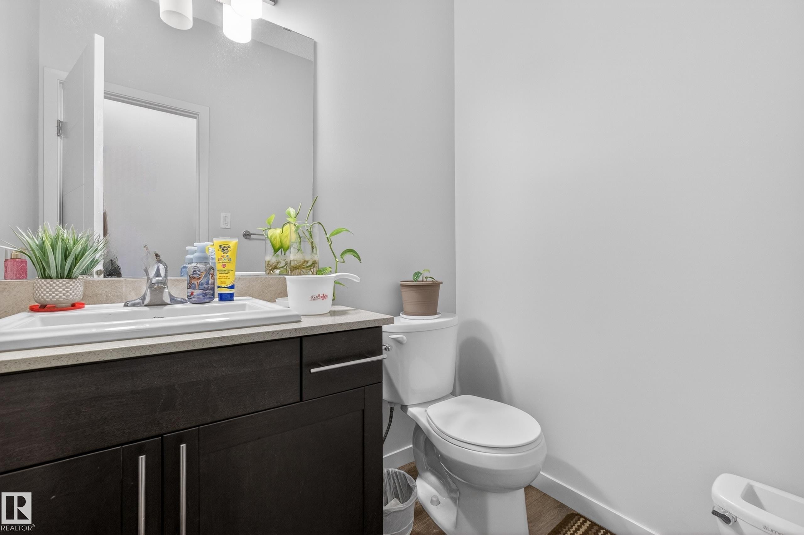 Bathroom featuring a dark wood-finish vanity with chrome hardware, an integrated sink, and light countertop - 1404 25 Avenue, Edmonton, AB