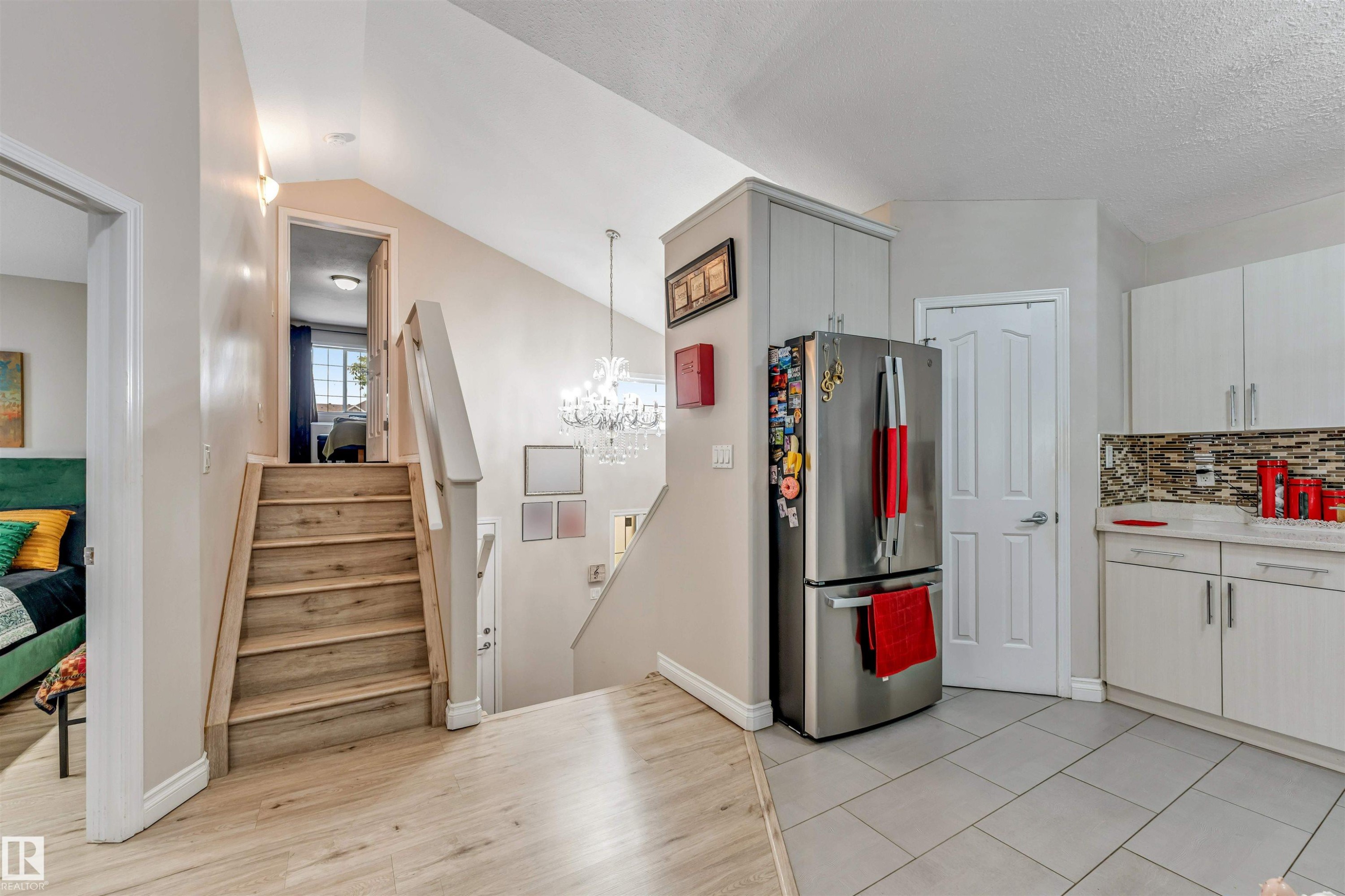 Kitchen area featuring light-toned cabinetry, light countertops, and a mosaic tile backsplash - 3519 22 Street Nw, Edmonton, AB