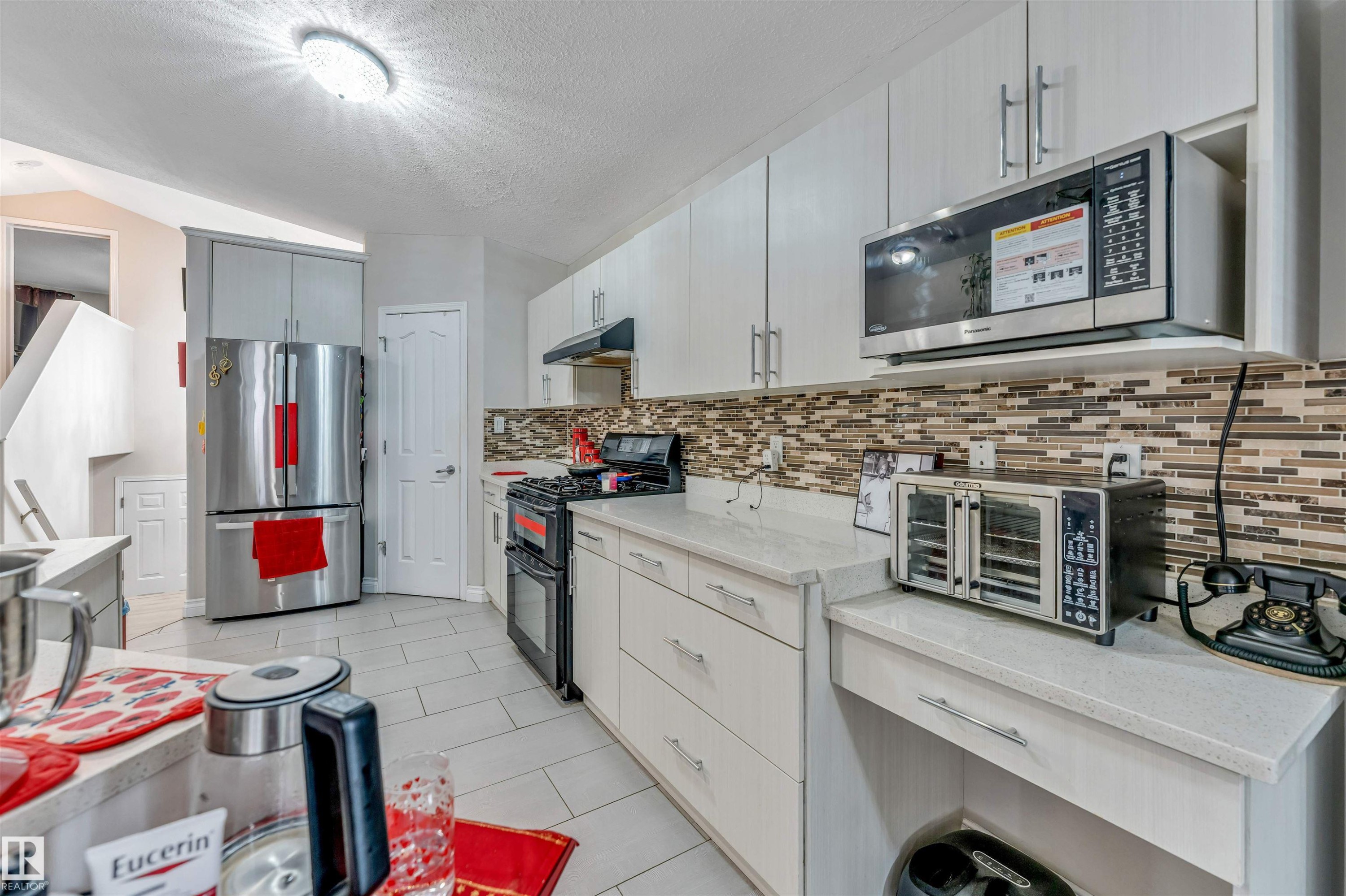 Contemporary kitchen with light-toned cabinetry, light countertops, and a mosaic tile backsplash - 3519 22 Street Nw, Edmonton, AB