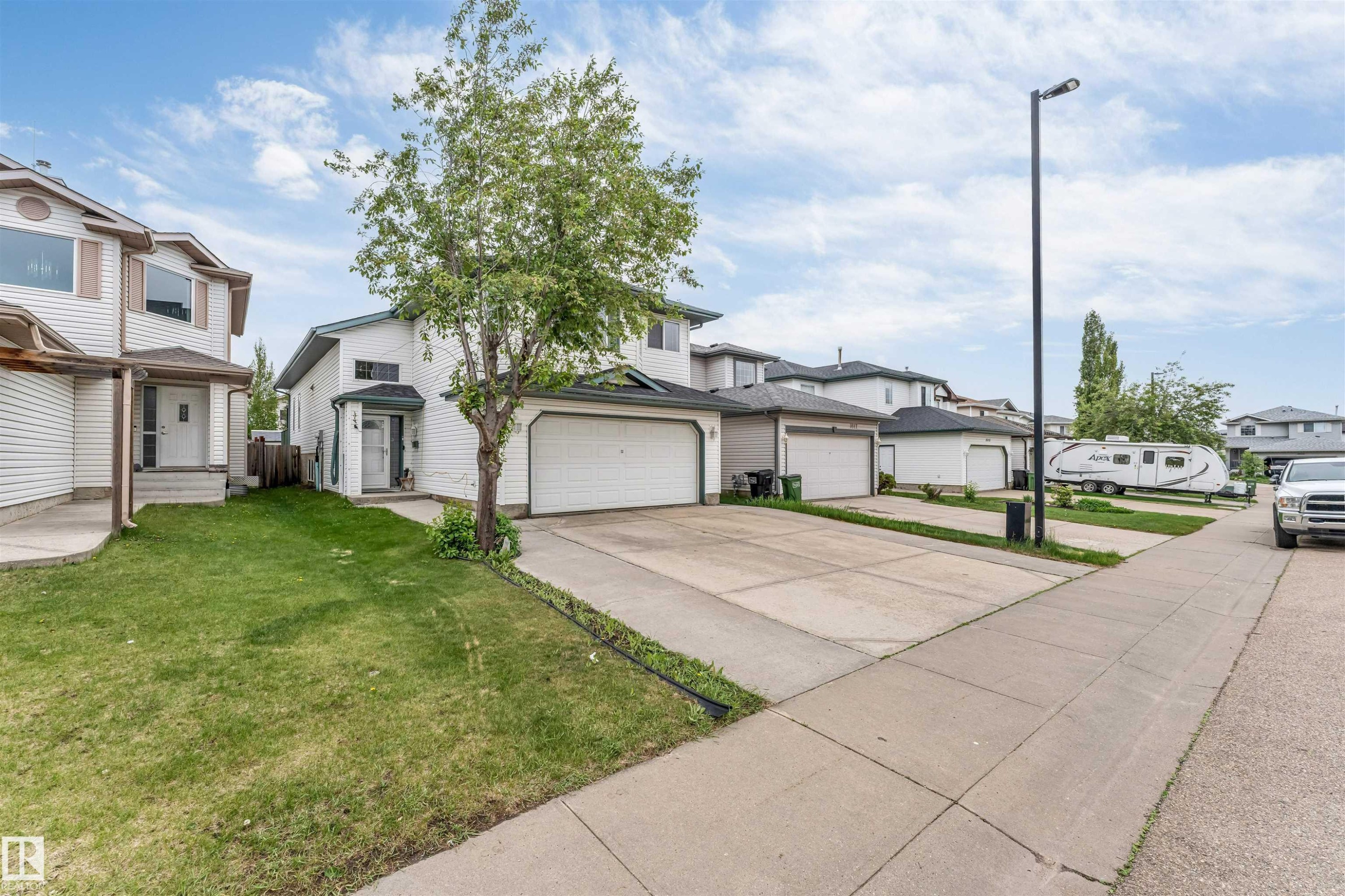 White two-story residence featuring an attached garage with a white sectional door - 3519 22 Street Nw, Edmonton, AB