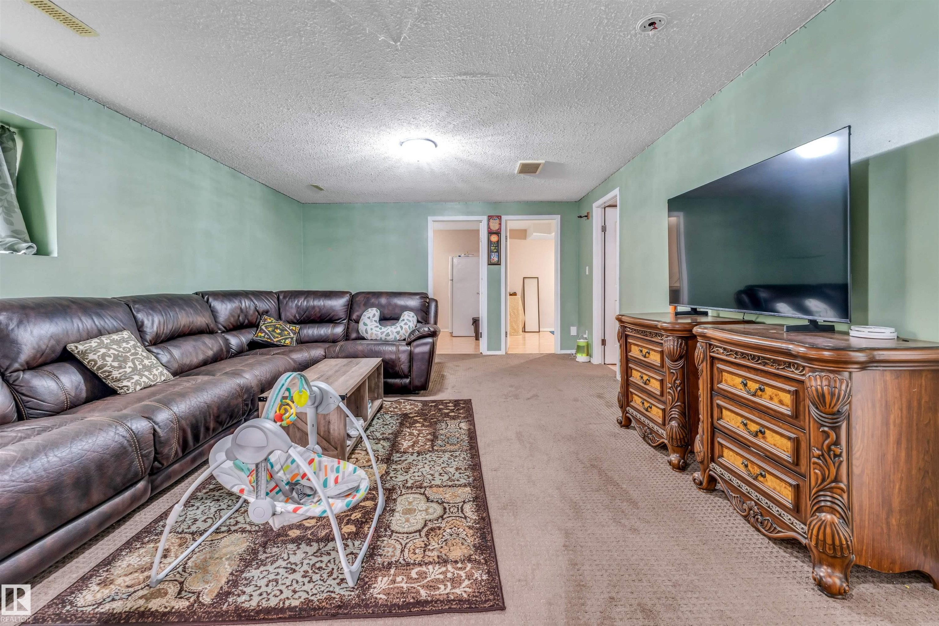 Spacious carpeted room featuring light green walls and multiple doorways - 3519 22 Street Nw, Edmonton, AB