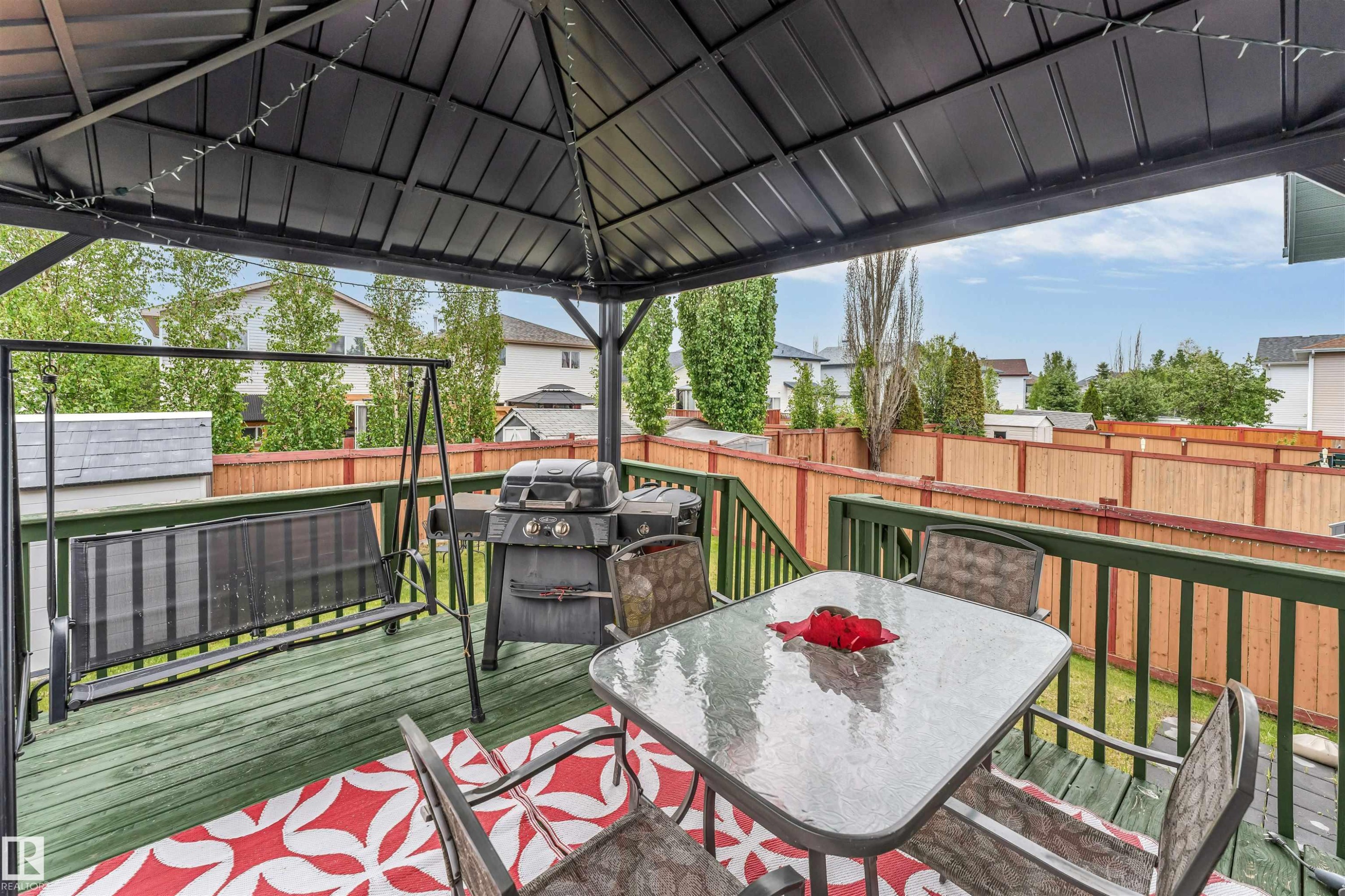 Expansive outdoor deck featuring a dark metal gazebo, green wood-finish decking, and a wood privacy fence - 3519 22 Street Nw, Edmonton, AB