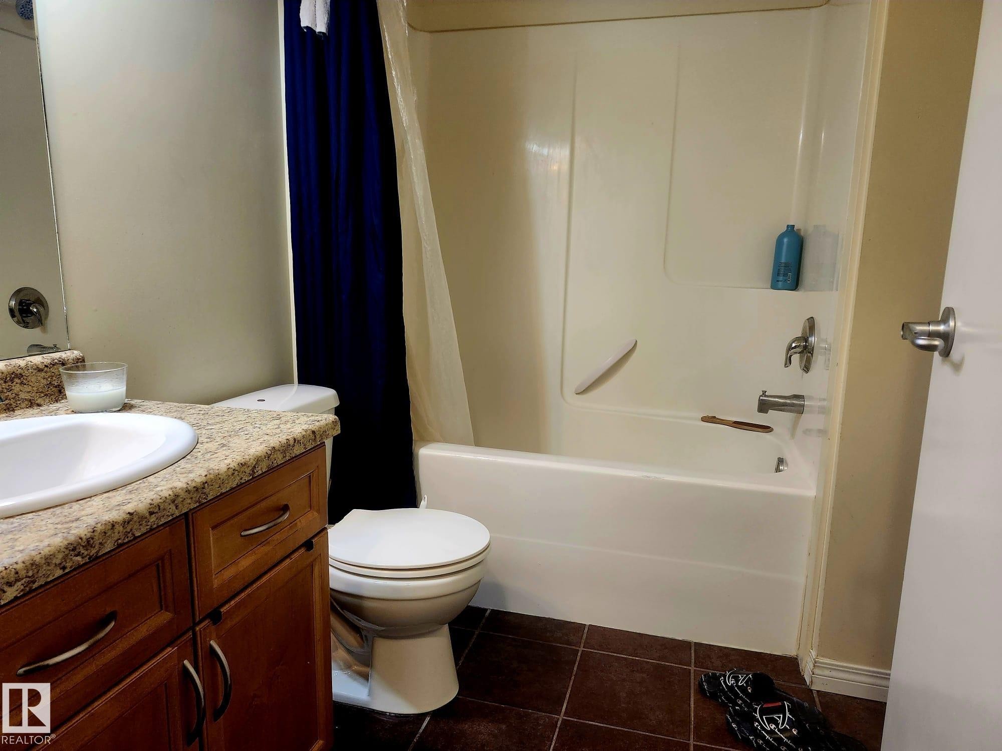 Bathroom featuring a vanity with a light-colored speckled countertop, an undermount sink, and wood-finish cabinetry with silver hardware - 425 4304 139 Avenue, Edmonton, AB