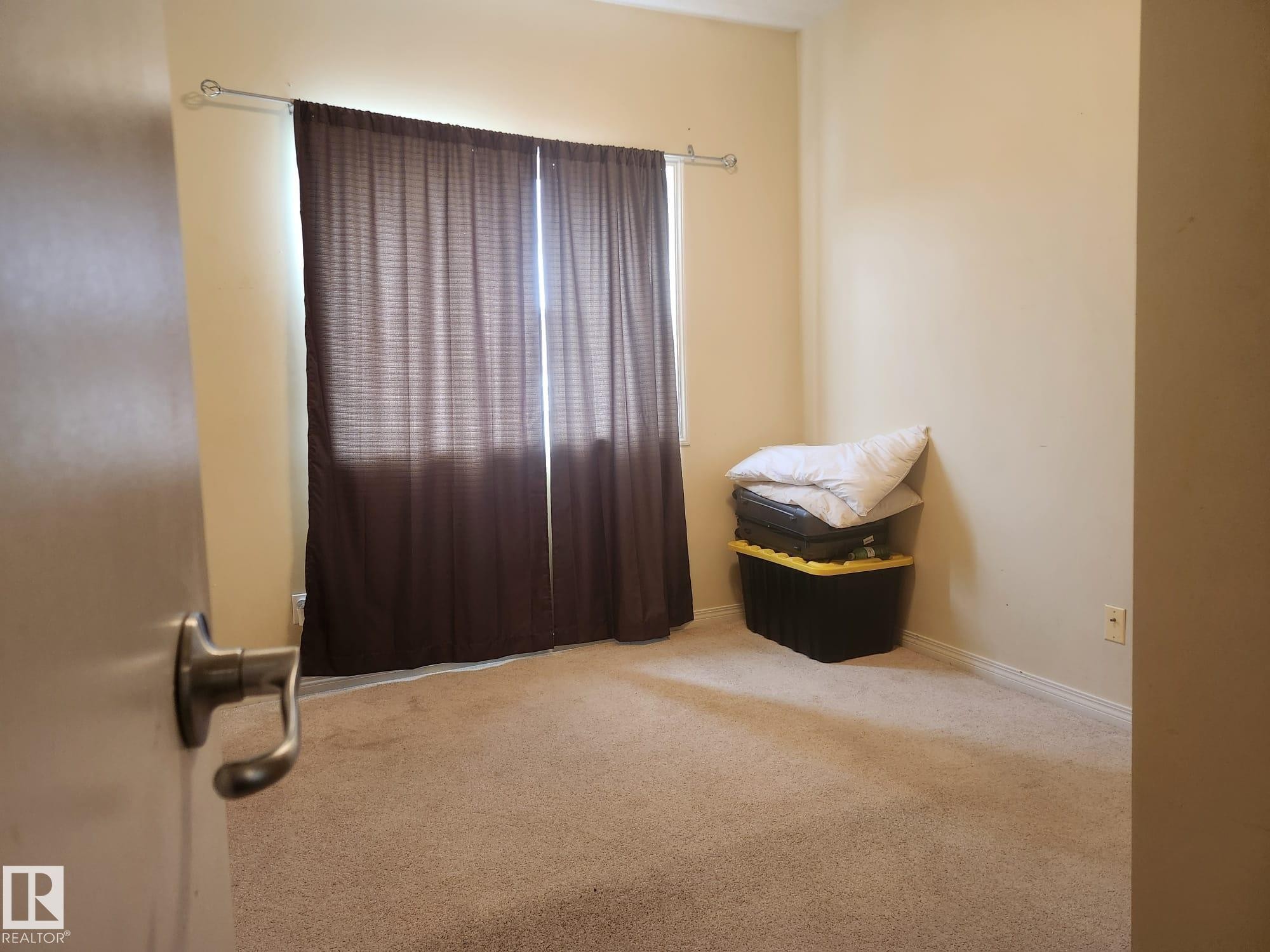 Carpeted room featuring a window with privacy blinds, neutral wall tones, and white baseboards - 425 4304 139 Avenue, Edmonton, AB