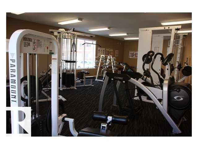 Fitness center featuring multiple exercise machines, textured dark carpeting, beige wall tones, and recessed lighting - 425 4304 139 Avenue, Edmonton, AB