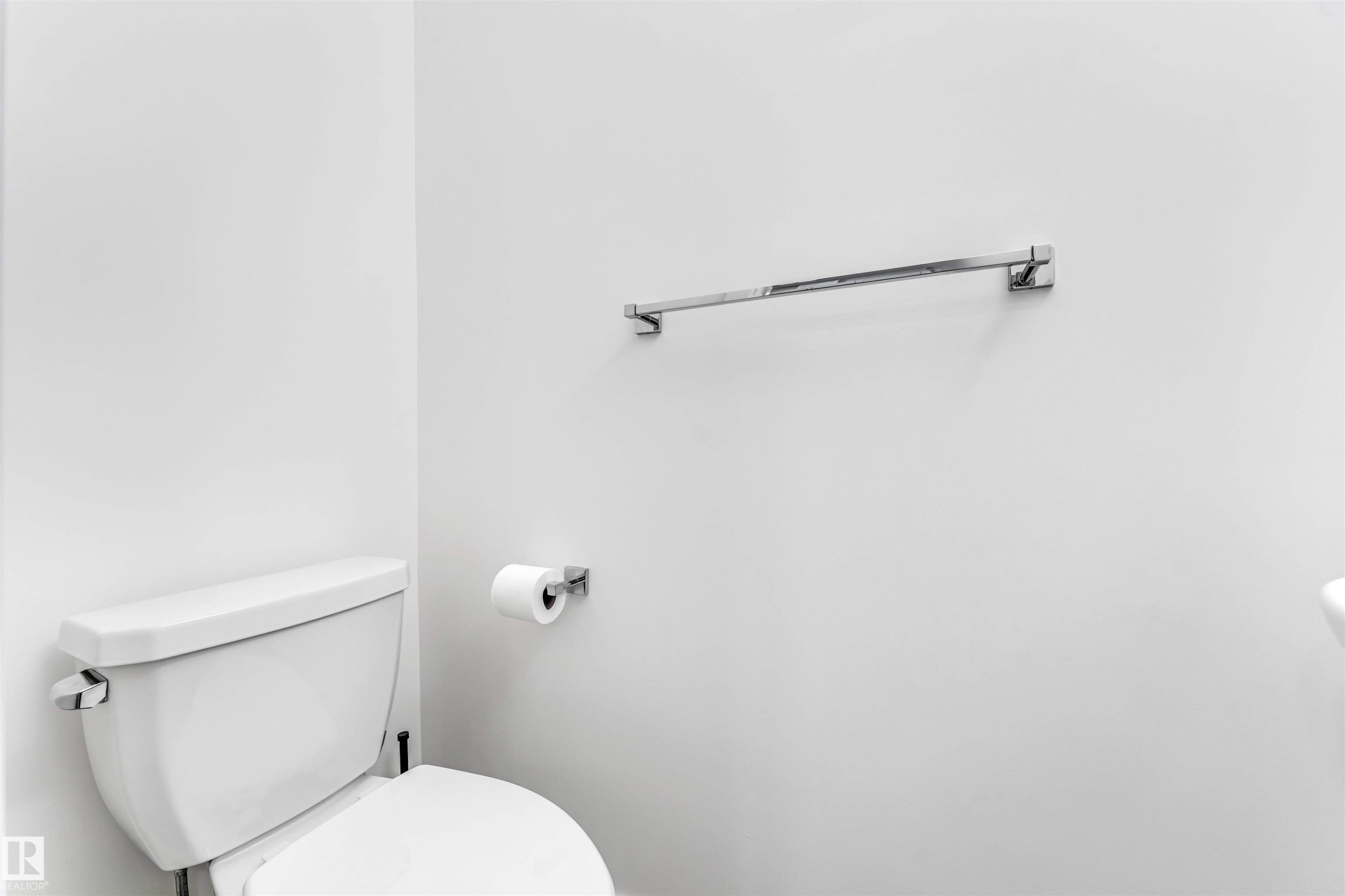 White wall finishes complemented by a contemporary white toilet and chrome fixtures, including a towel bar and toilet paper holder - 45 2710 66 Street, Edmonton, AB