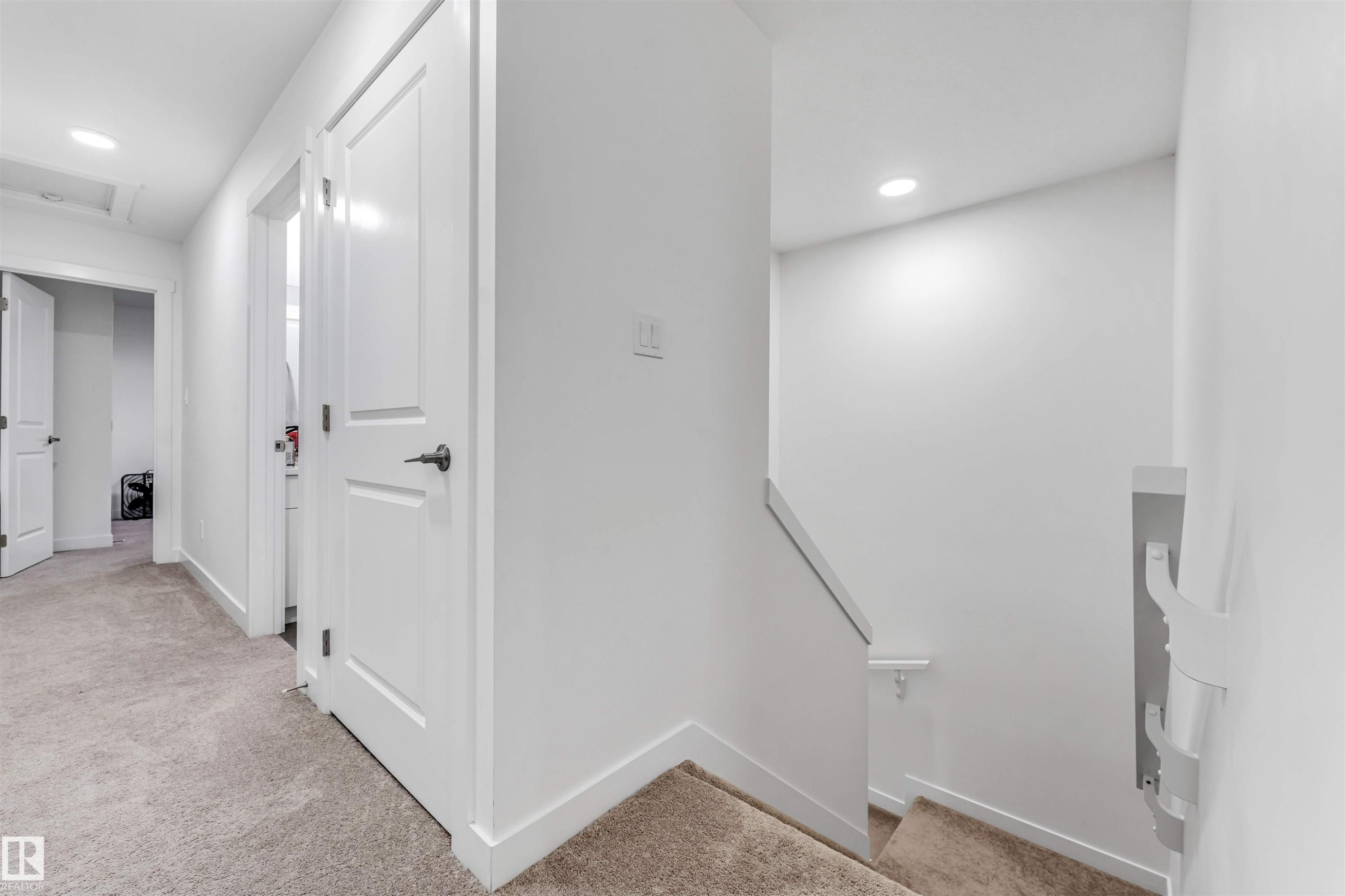 Upper-level hallway featuring neutral carpeting, recessed lighting, white interior doors, and crisp white trim - 45 2710 66 Street, Edmonton, AB
