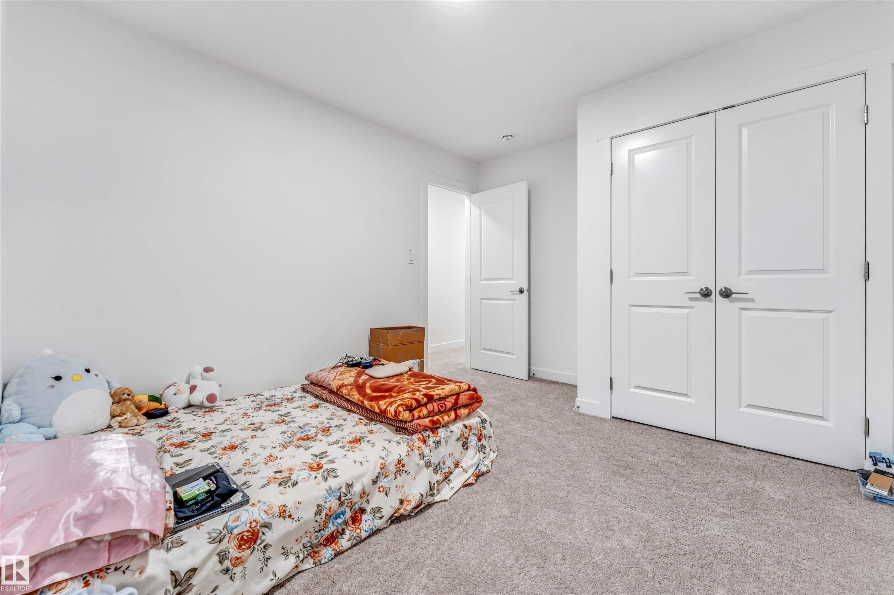 Bedroom featuring light-colored wall-to-wall carpeting, white painted walls, and a white paneled door - 45 2710 66 Street, Edmonton, AB