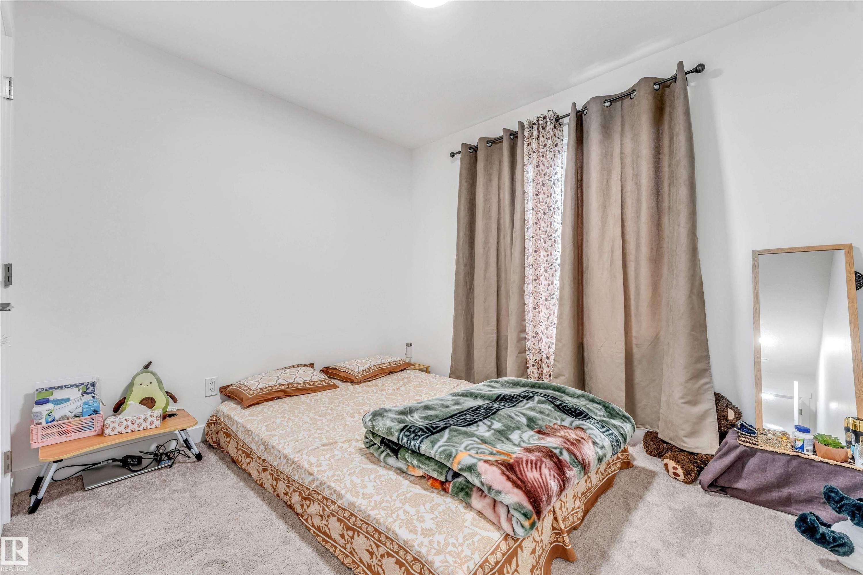 Bedroom featuring wall-to-wall carpeting, white painted walls, a window with curtain rod and drapes, and a ceiling-mounted light fixture - 45 2710 66 Street, Edmonton, AB