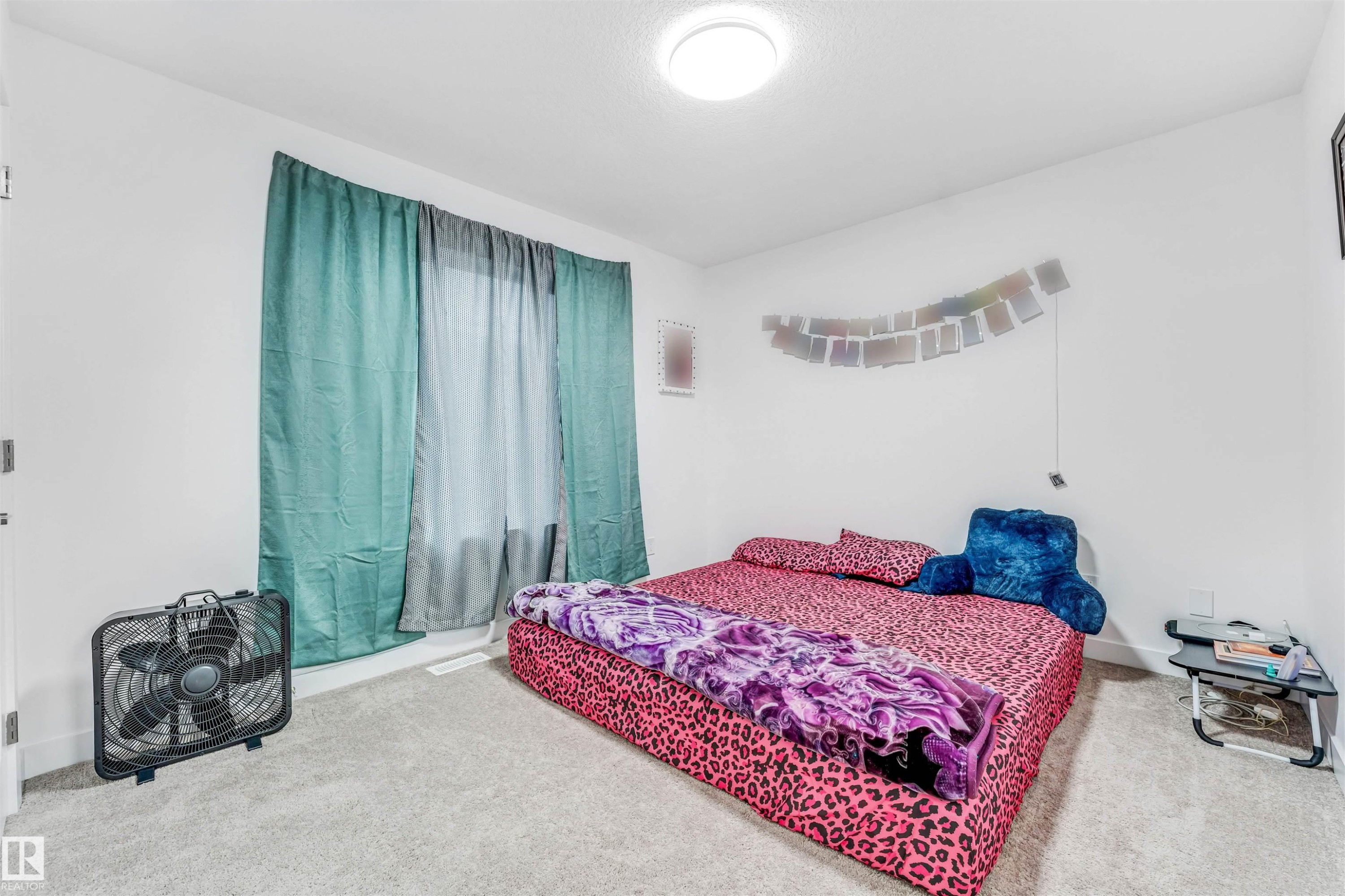 Carpeted interior space featuring a window with teal and sheer white drapes - 45 2710 66 Street, Edmonton, AB