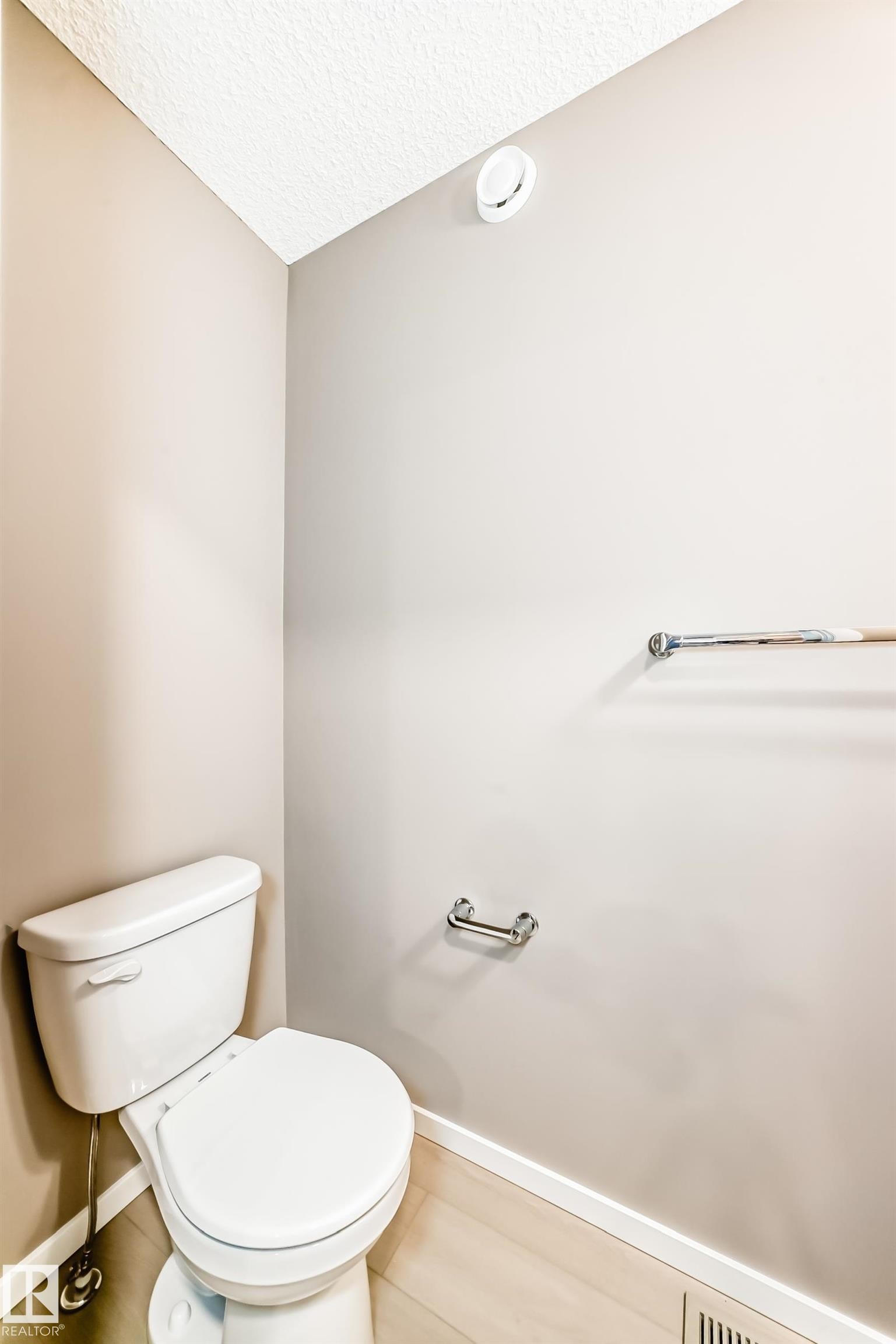 White toilet with chrome flush lever, light wood-finish flooring, and neutral wall paint - 1210 Stoneside Road, Sherwood Park, AB - Indoor Photo Showing Bathroom