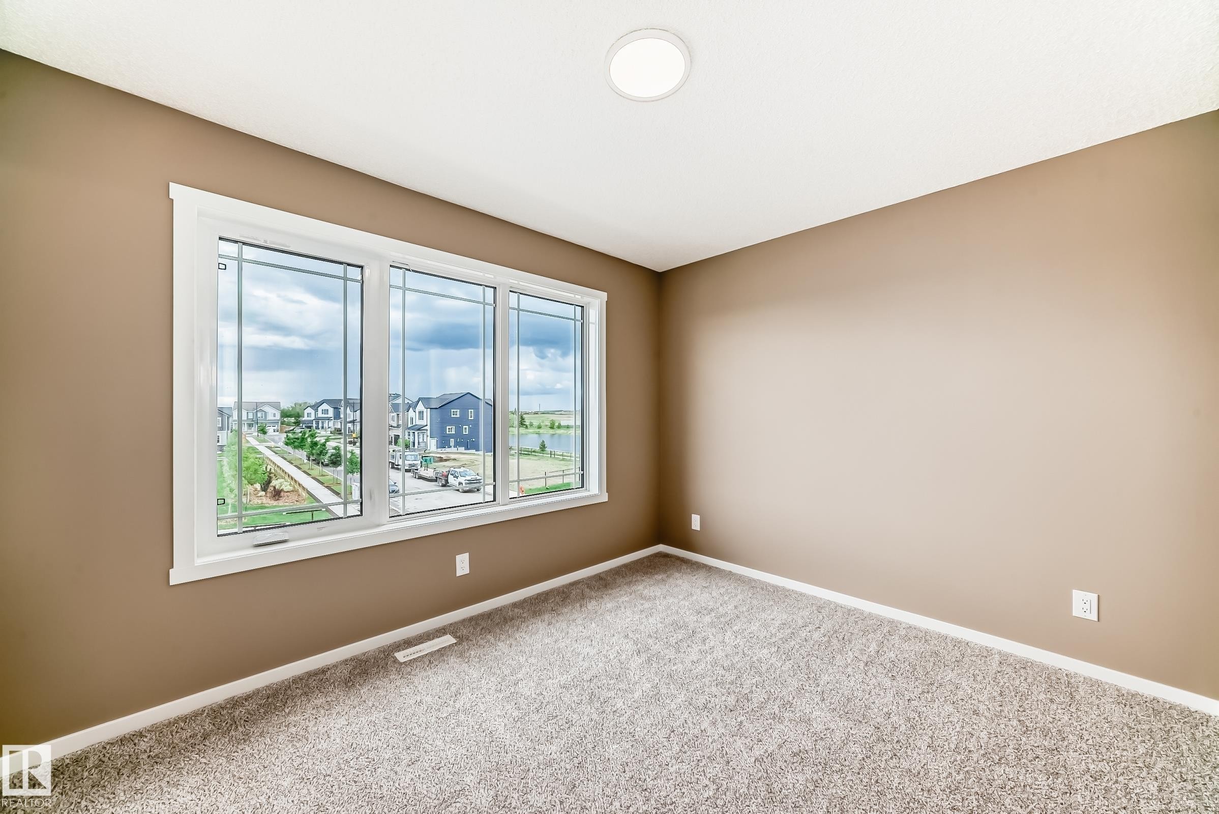 Expansive window featuring decorative grilles, white trim, and a surrounding neighborhood landscape - 1210 Stoneside Road, Sherwood Park, AB - Indoor Photo Showing Other Room