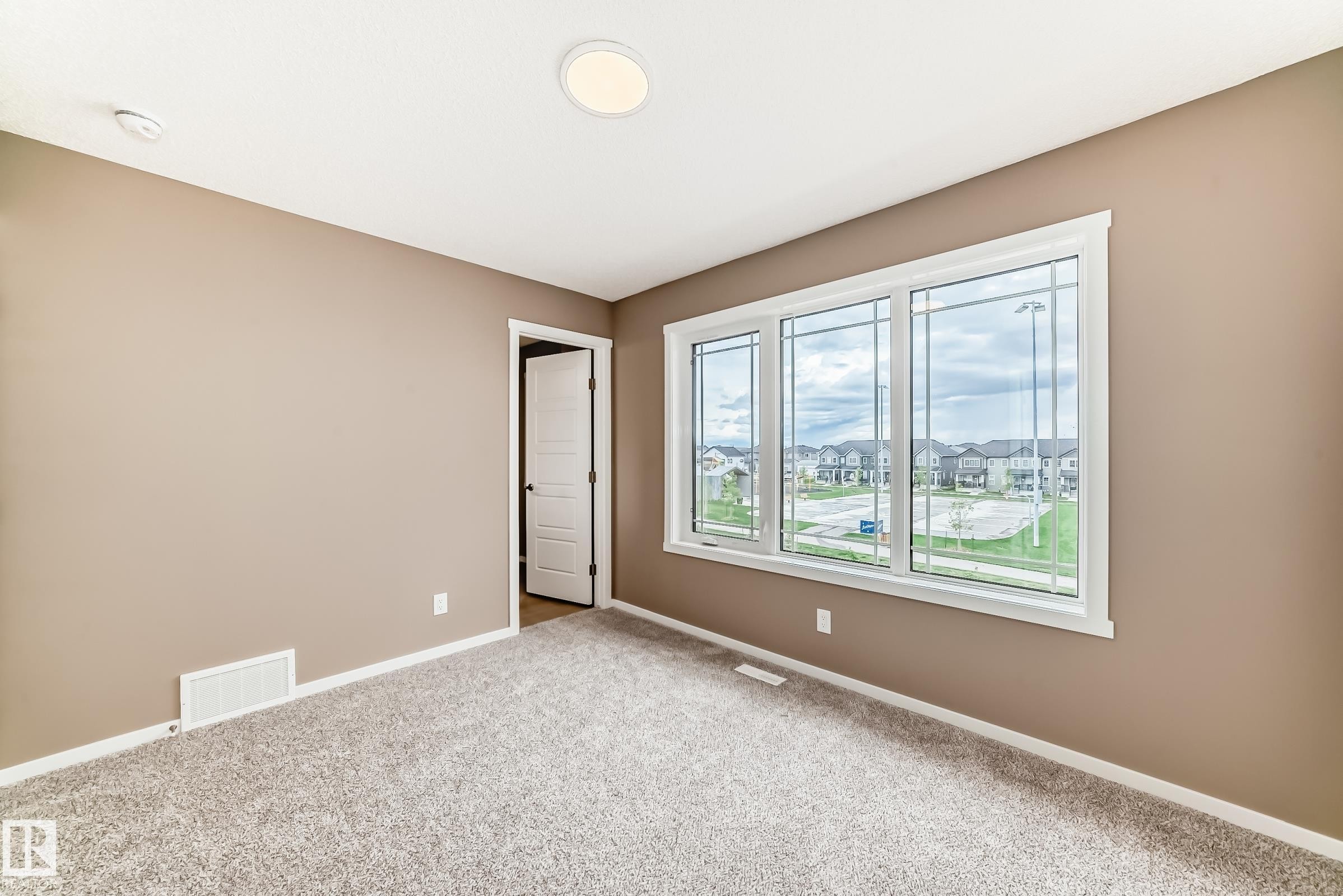 Inviting room featuring a multi-pane window, neutral-toned walls, gray carpet, white trim, and a flush-mount ceiling light - 1210 Stoneside Road, Sherwood Park, AB - Indoor Photo Showing Other Room