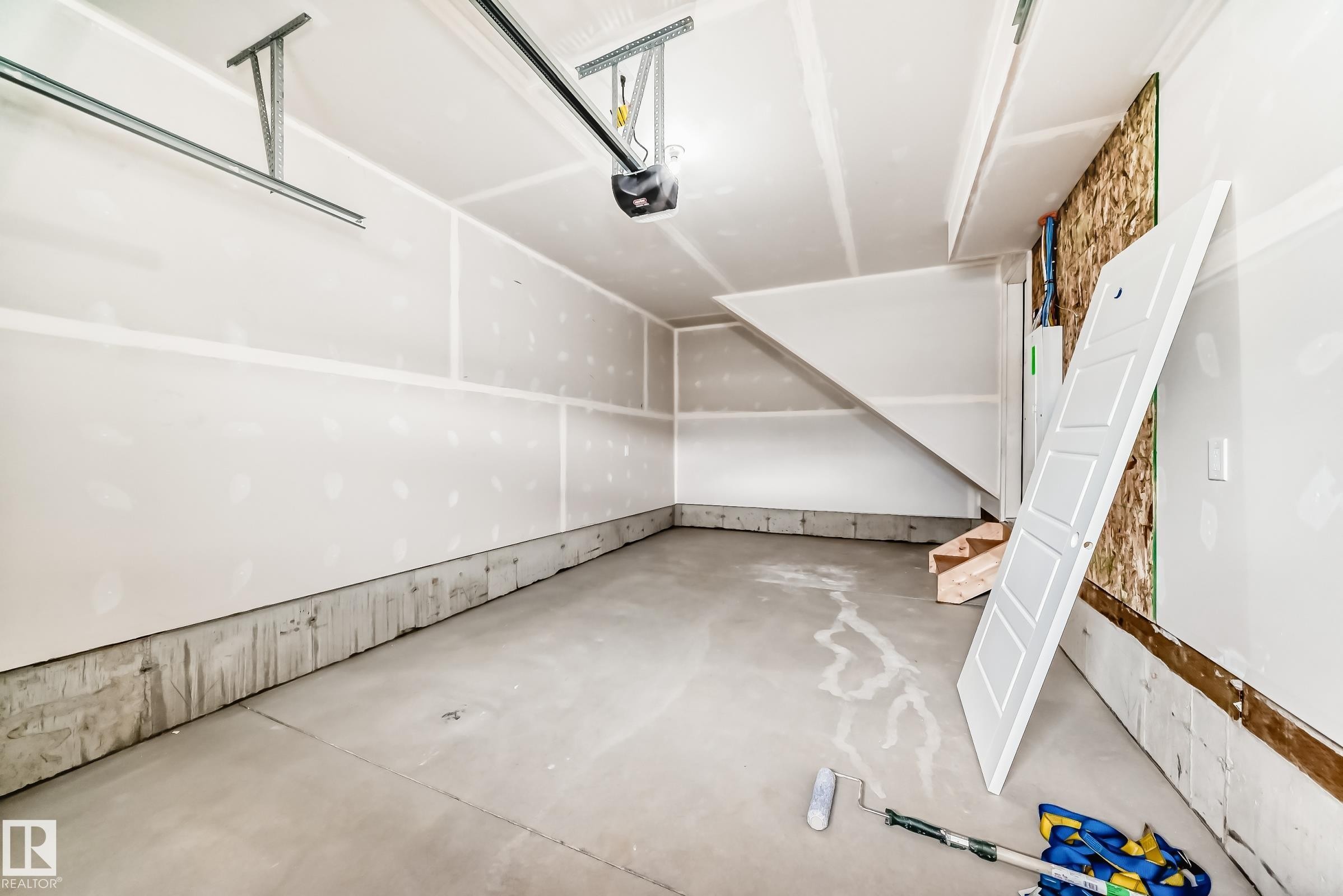 Unfinished garage interior featuring a concrete floor, gypsum board walls, and an overhead garage door track system - 1210 Stoneside Road, Sherwood Park, AB - Indoor Photo Showing Other Room