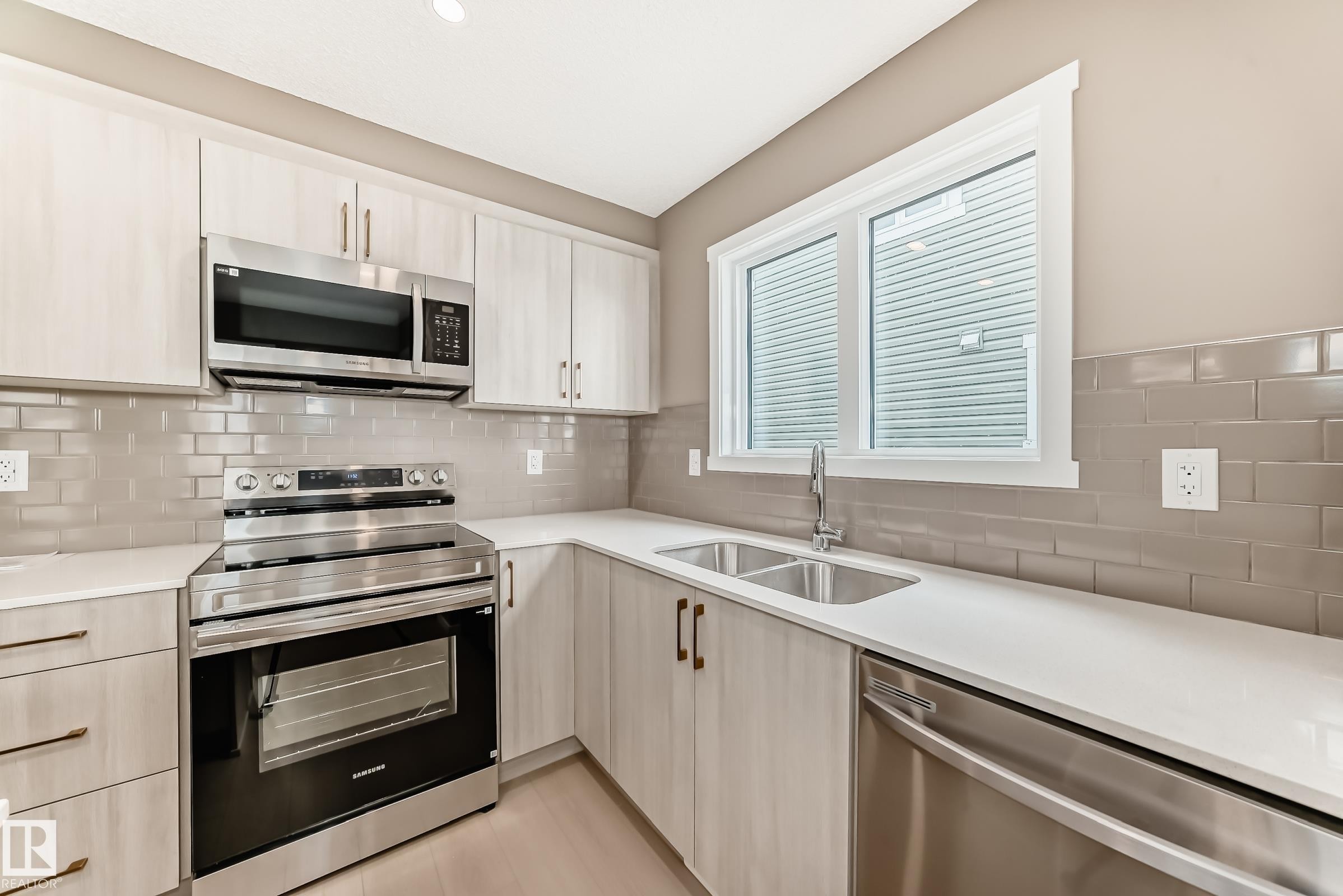Contemporary kitchen featuring light wood-finish cabinetry, stainless steel appliances, white countertops, and a gray subway tile backsplash - 1210 Stoneside Road, Sherwood Park, AB - Indoor Photo Showing Kitchen With Double Sink With Upgraded Kitchen