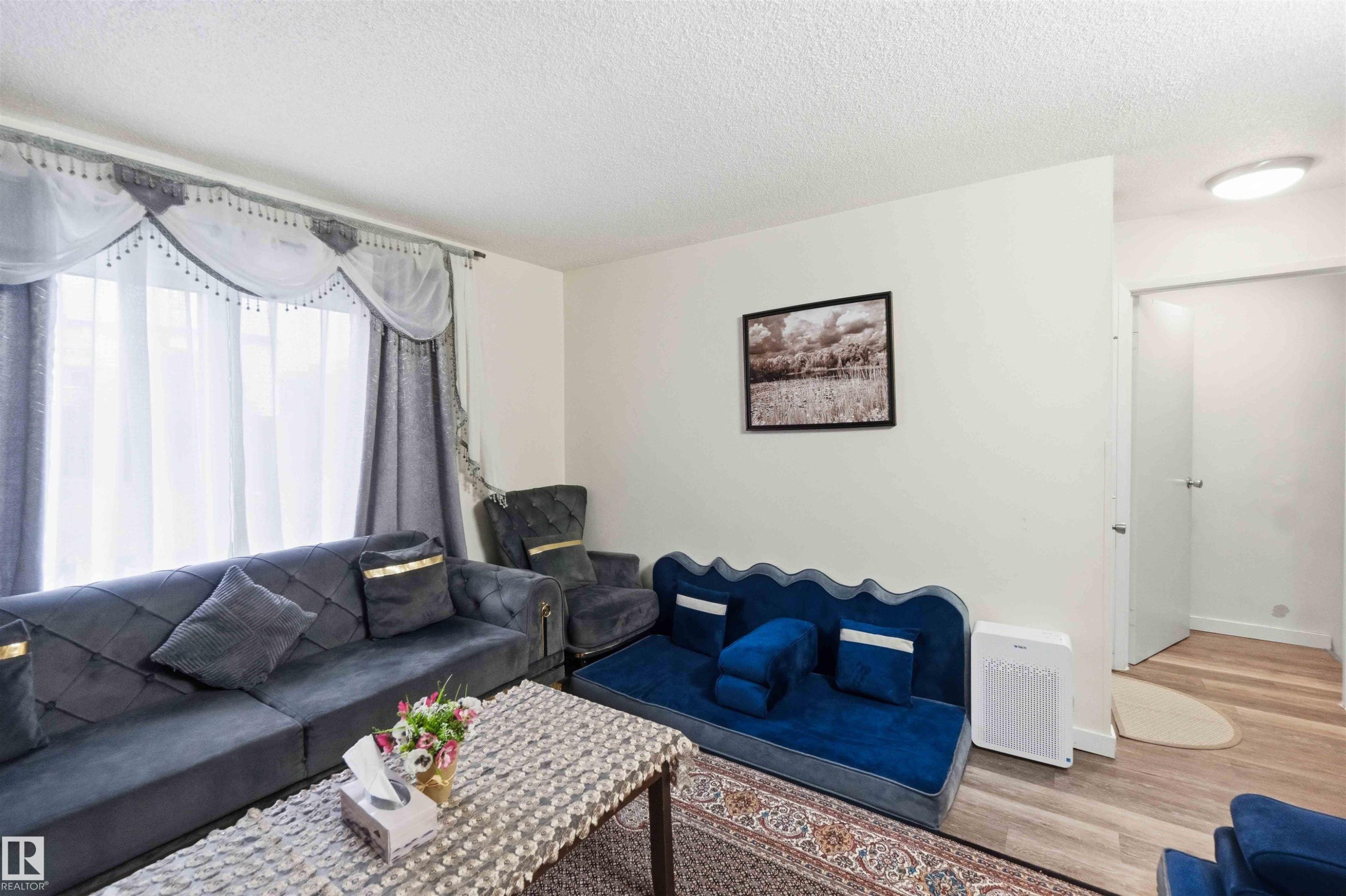 Bright living space featuring light-toned walls and wood-finish flooring - 203 11421 34 Street Nw, Edmonton, AB