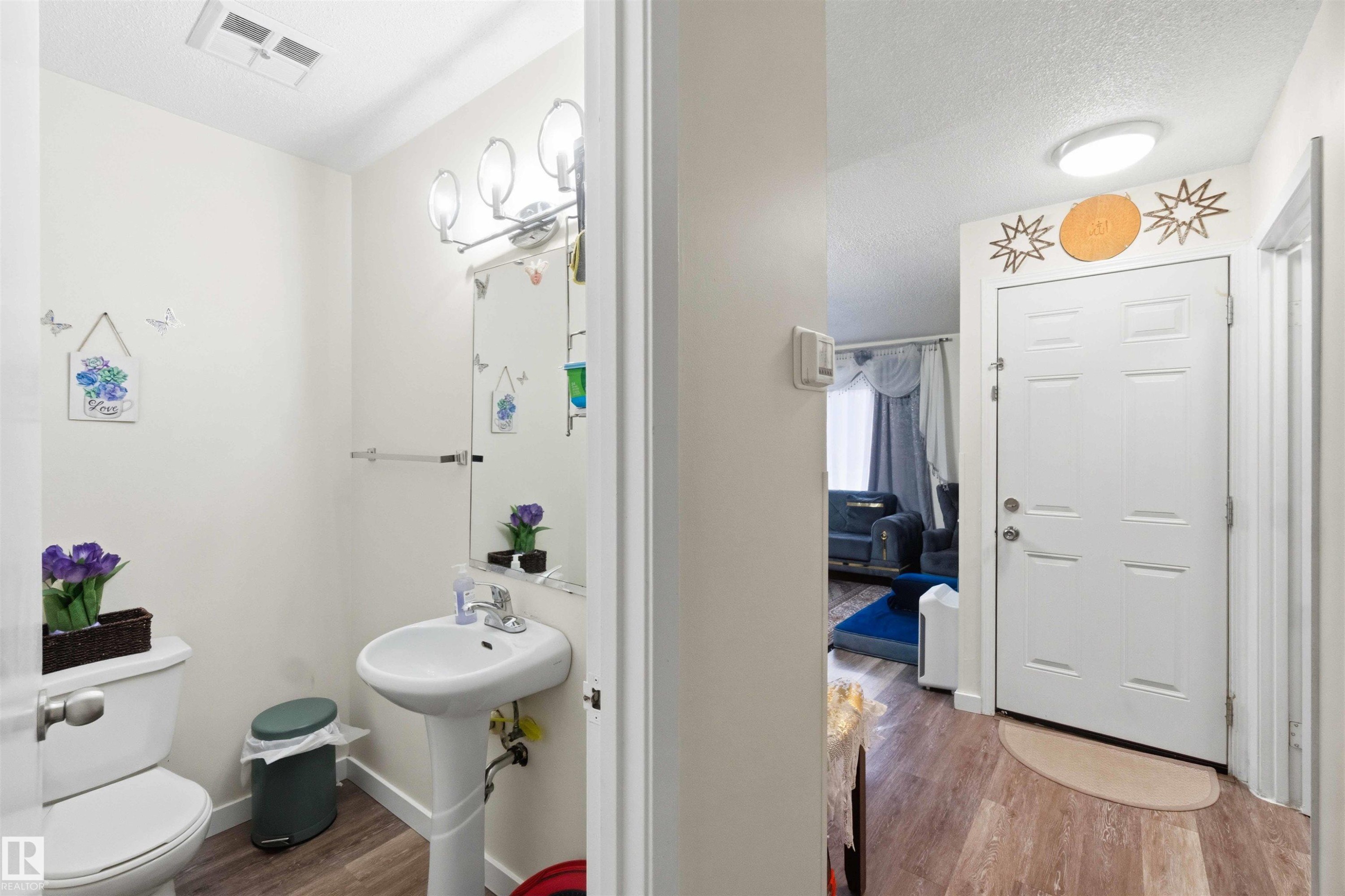 Powder room featuring a pedestal sink, toilet, and wood-finish flooring - 203 11421 34 Street Nw, Edmonton, AB