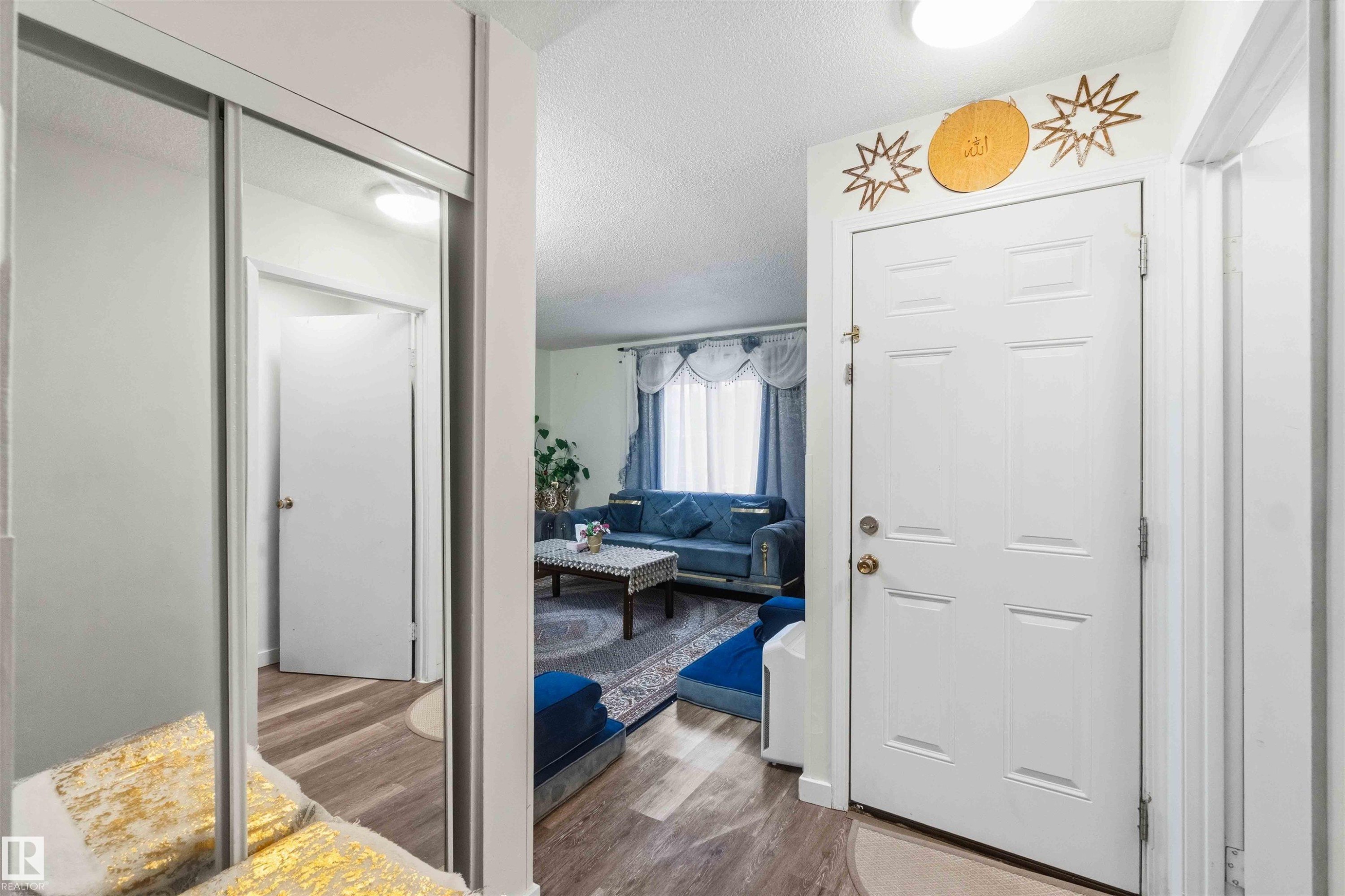 Entryway featuring wood-finish flooring and a full-length mirrored closet door - 203 11421 34 Street Nw, Edmonton, AB
