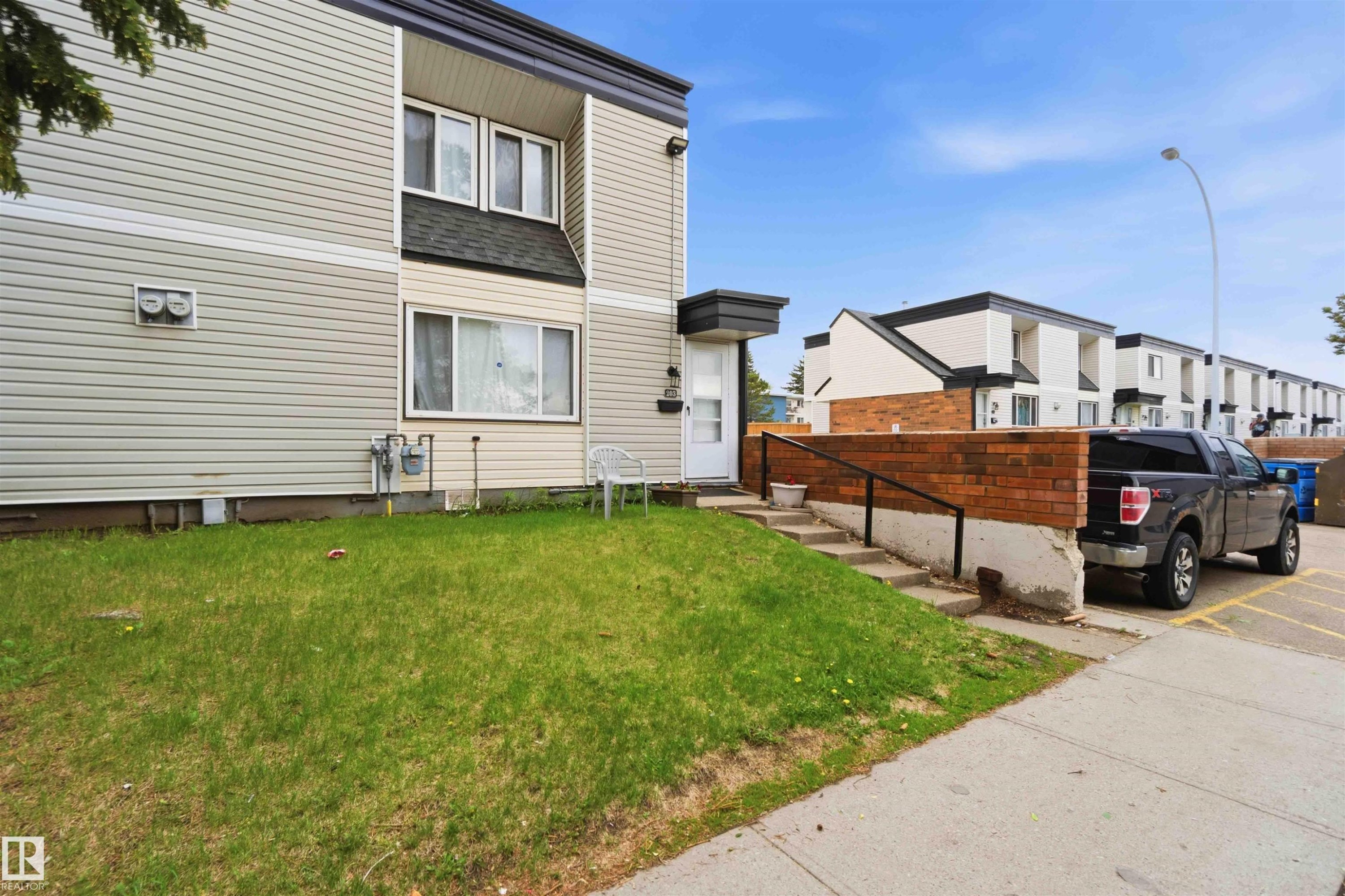 Multi-level residence featuring light-toned horizontal siding and a dark roofline - 203 11421 34 Street Nw, Edmonton, AB