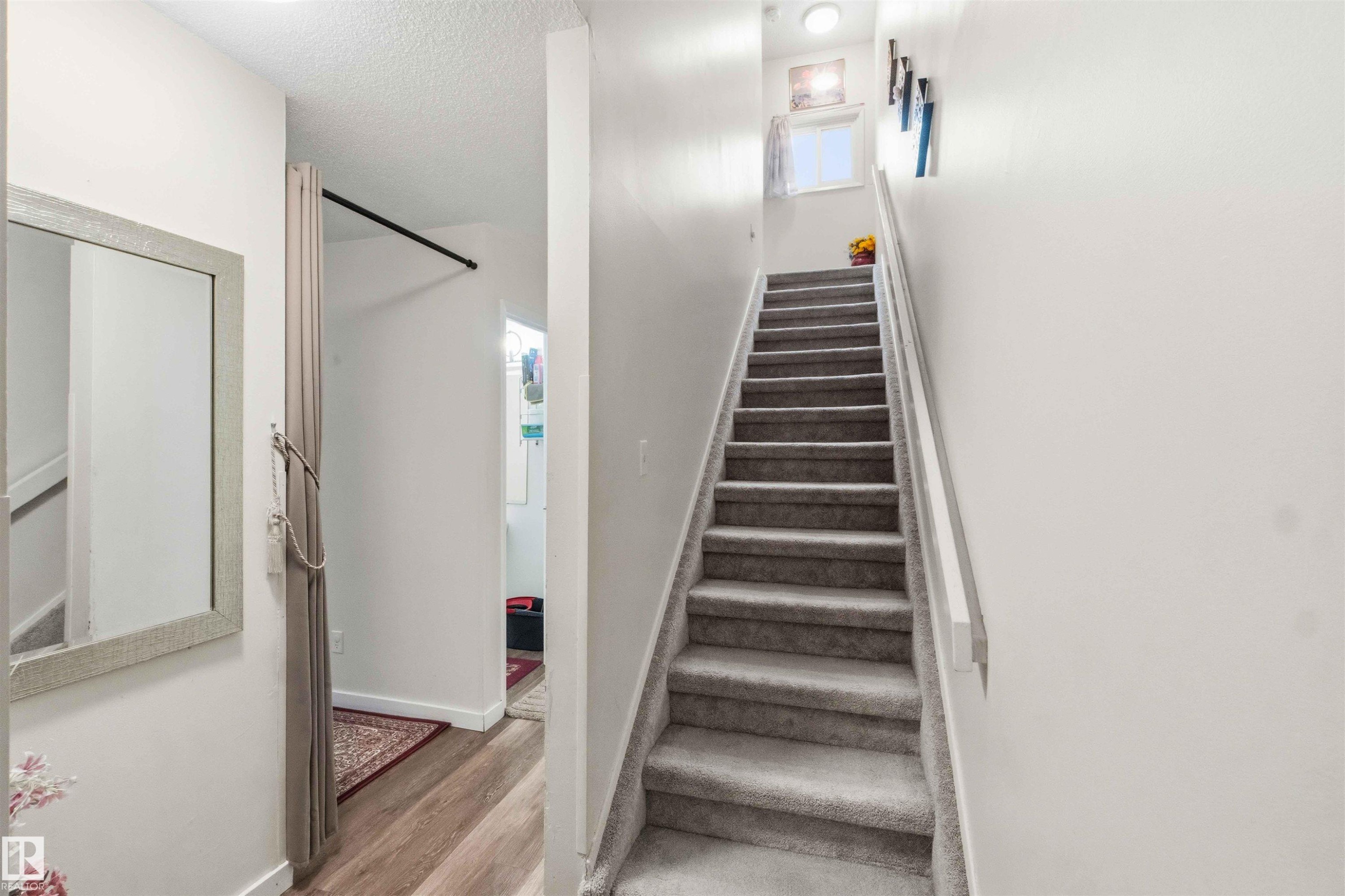 Carpeted staircase with white handrail ascending to an upper level - 203 11421 34 Street Nw, Edmonton, AB