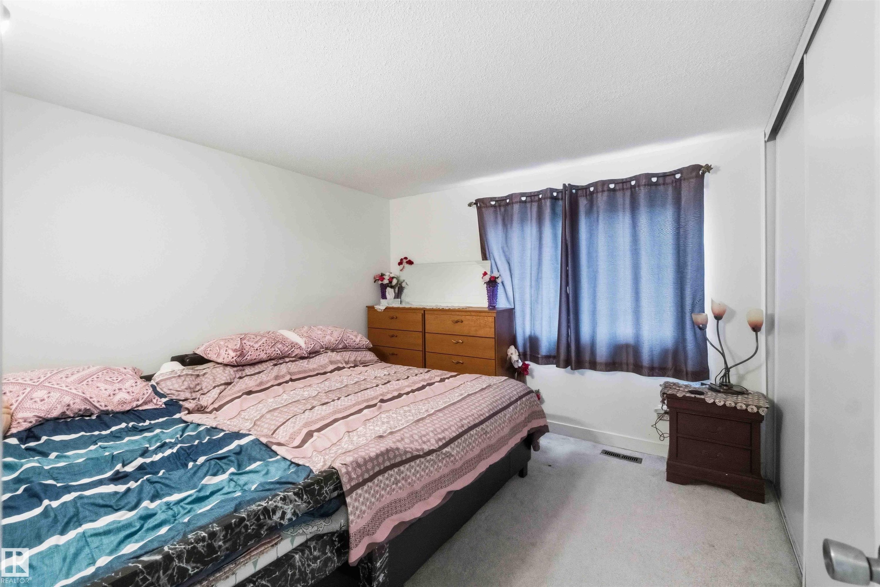 Carpeted flooring, white walls, and a window with dark curtains define this room - 203 11421 34 Street Nw, Edmonton, AB