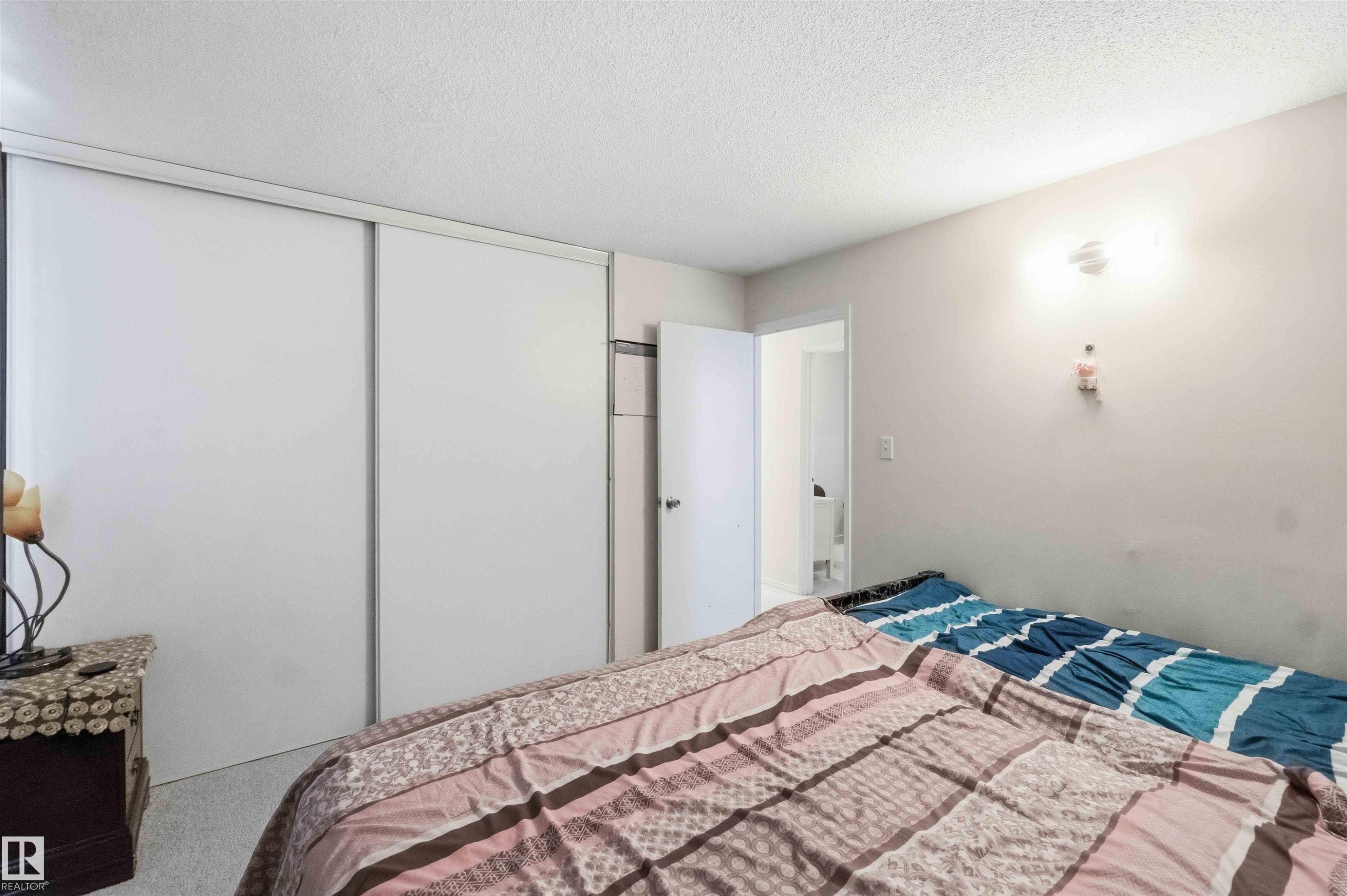 Room featuring white sliding closet doors, light-colored walls, and a textured ceiling - 203 11421 34 Street Nw, Edmonton, AB