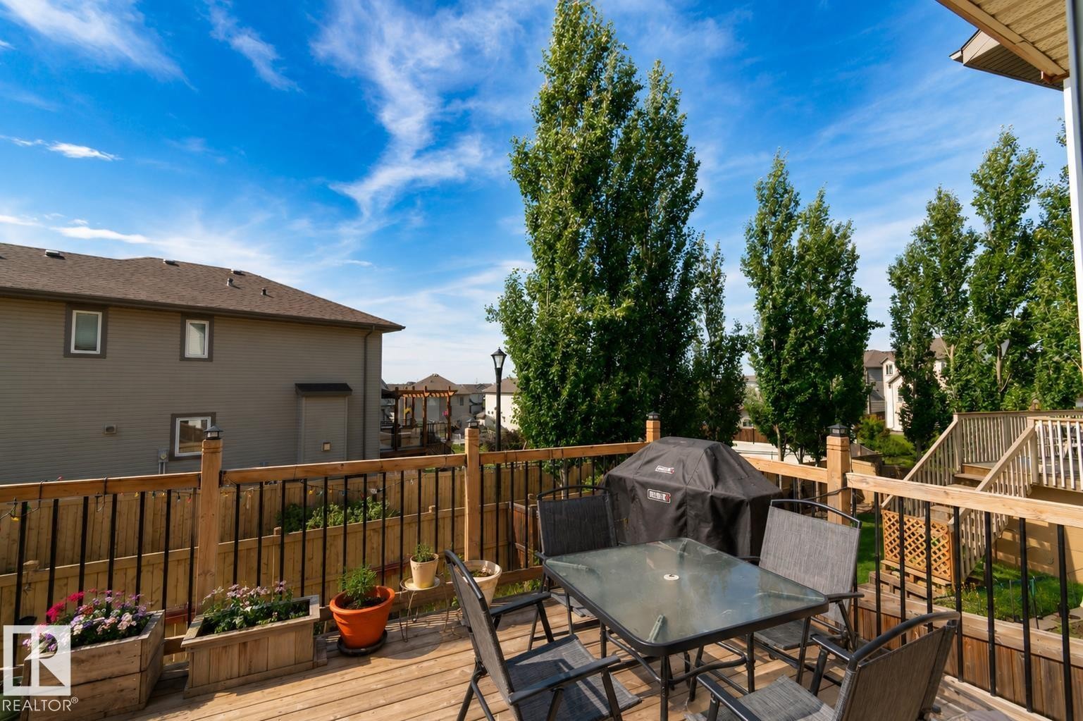 Expansive wood-finish deck with black metal spindle railings and privacy fencing - 1840 56 Street, Edmonton, AB
