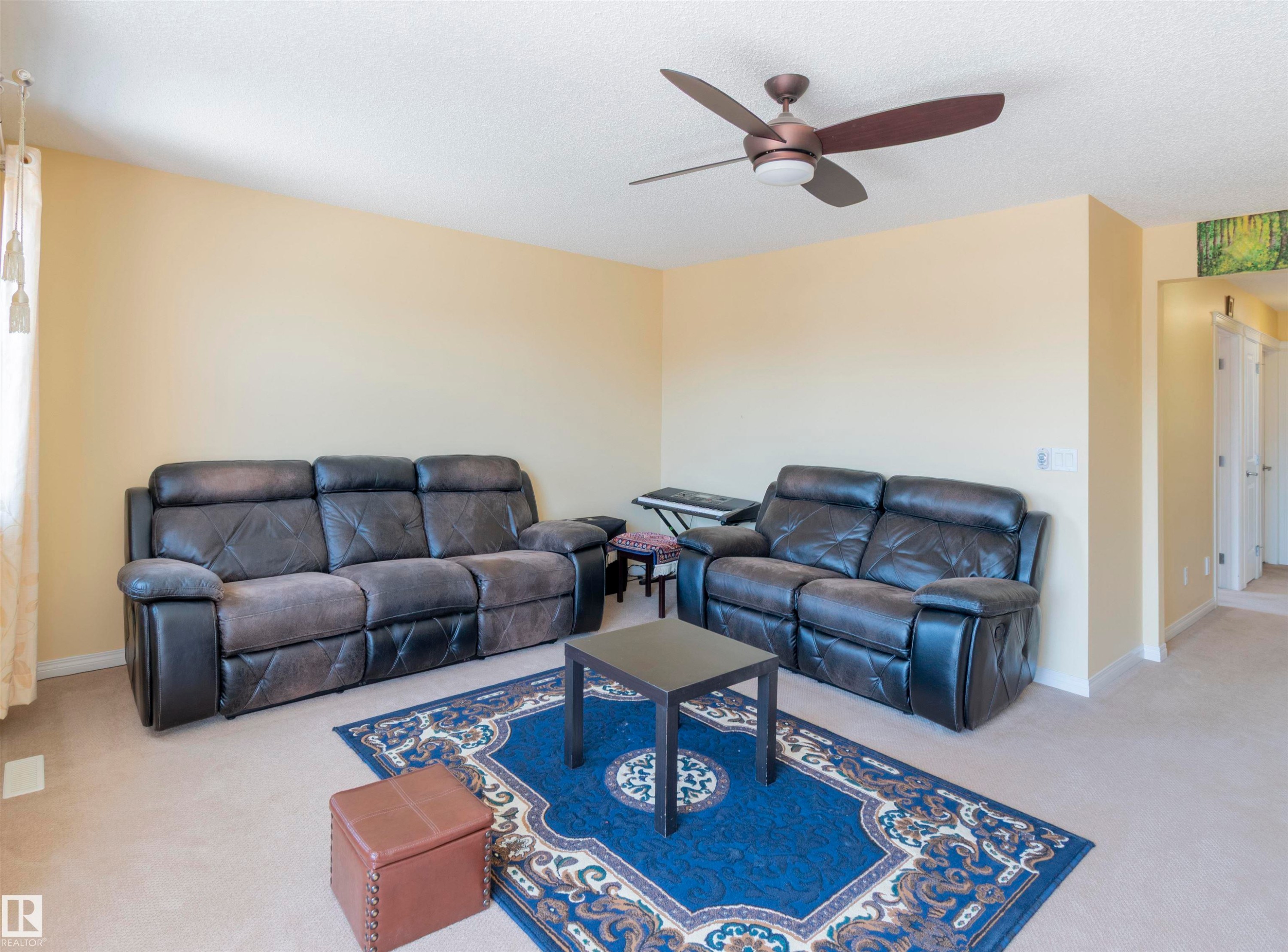 Living area featuring neutral wall paint and carpeting, a ceiling fan with integrated lighting, and white trim - 1840 56 Street, Edmonton, AB