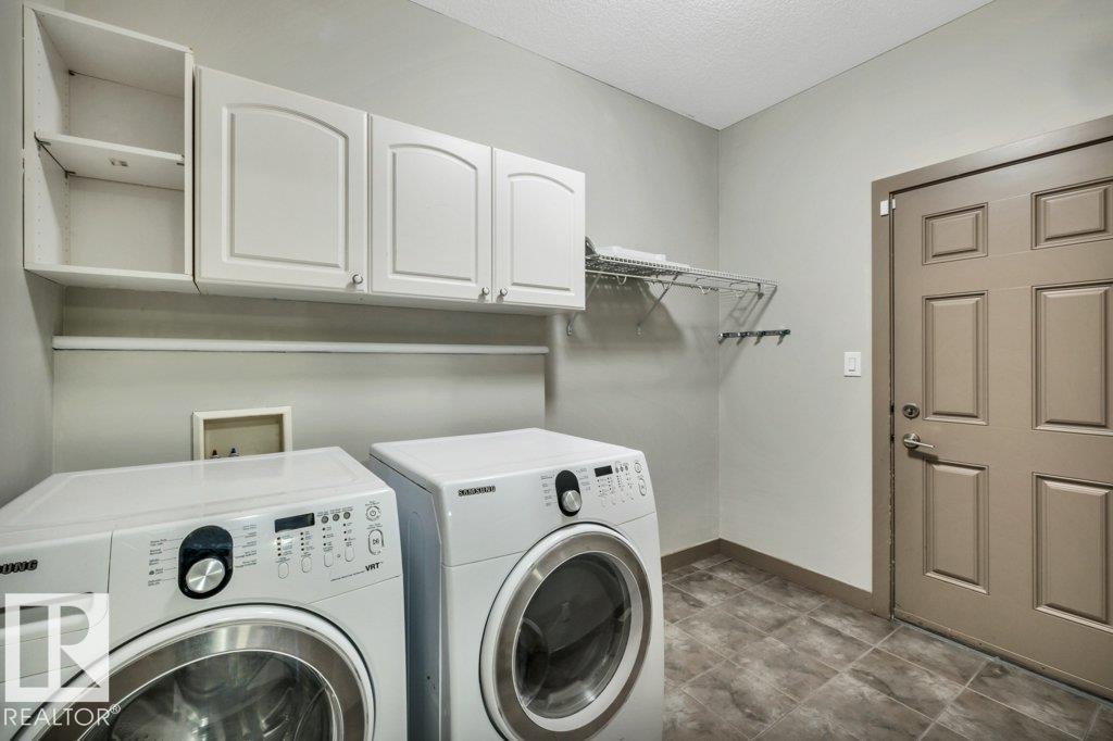 Dedicated laundry area featuring white upper cabinetry, open shelving, a hanging rack, and durable tile flooring - 1107 Chahley Crest, Edmonton, AB