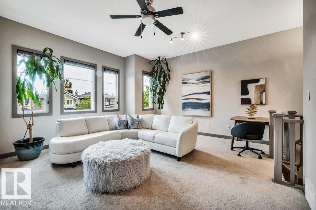 Upper-level landing featuring light gray carpeting, multiple windows with gray trim, a ceiling fan with integrated lighting, and track lighting fixtures - 1107 Chahley Crest, Edmonton, AB