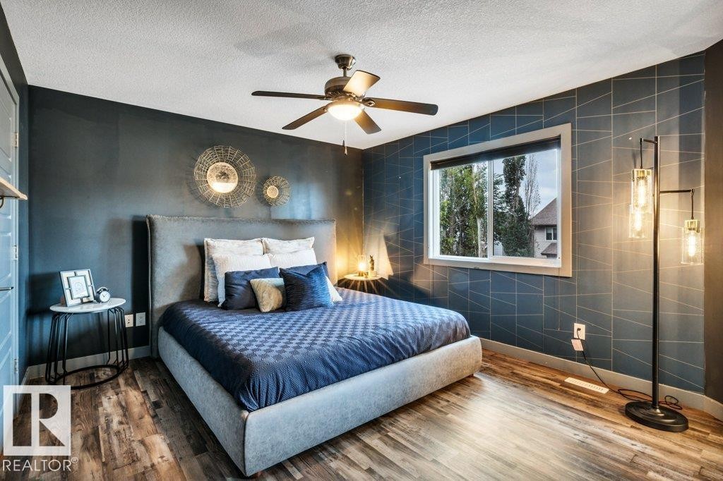 Bedroom featuring wood-finish flooring, a ceiling fan, and a window with white trim - 1107 Chahley Crest, Edmonton, AB