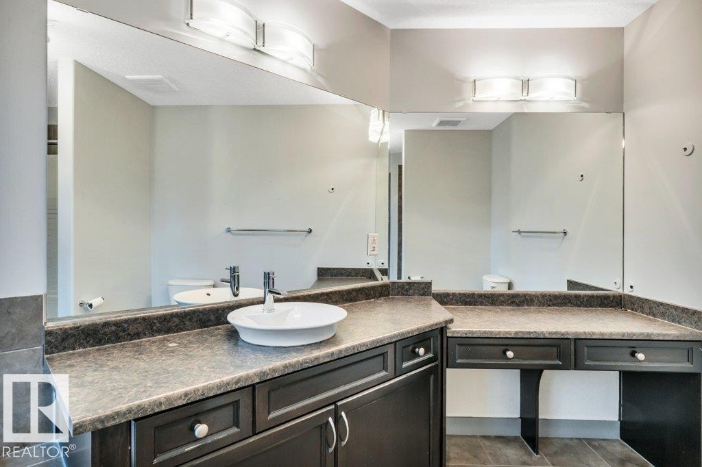 Bathroom vanity featuring a vessel sink, dark wood-finish cabinetry, and a spacious countertop - 1107 Chahley Crest, Edmonton, AB