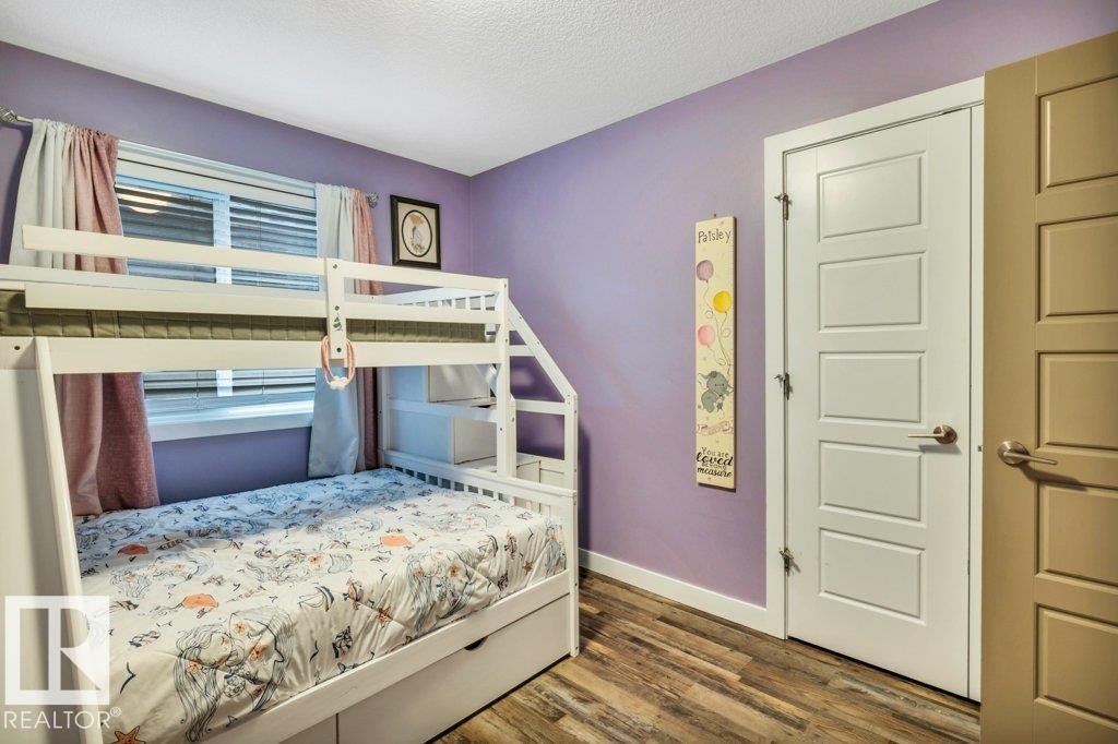 Room featuring wood-finish flooring, a white five-panel door, and a multi-pane window with blinds - 1107 Chahley Crest, Edmonton, AB