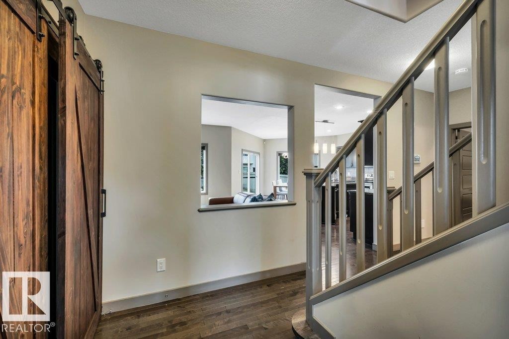 Entryway featuring a wood-finish barn door, hardwood flooring, and a staircase with painted balusters - 1107 Chahley Crest, Edmonton, AB
