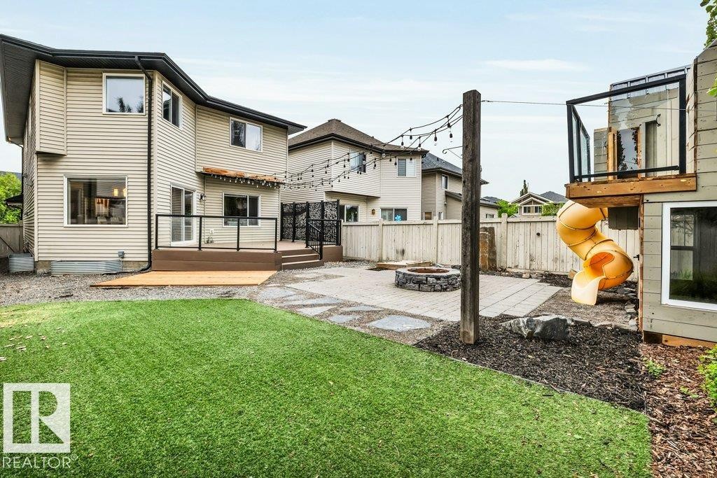 Expansive backyard featuring a manicured lawn, paver patio, and stone fire pit - 1107 Chahley Crest, Edmonton, AB