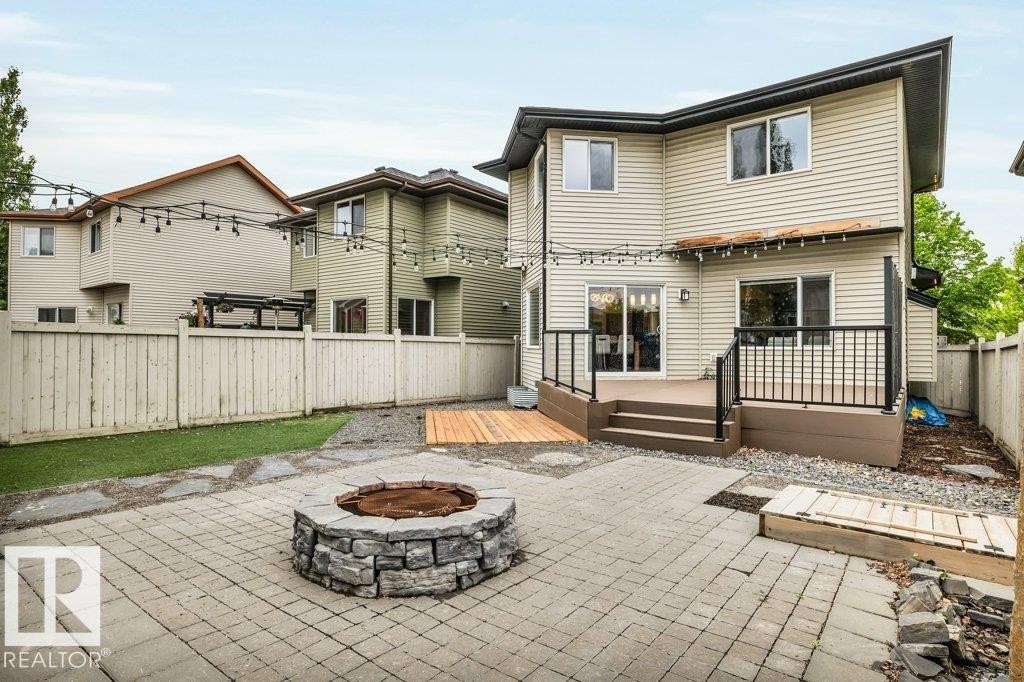 Paver patio featuring a stone fire pit, wood-finish decking, and low-maintenance landscaping - 1107 Chahley Crest, Edmonton, AB