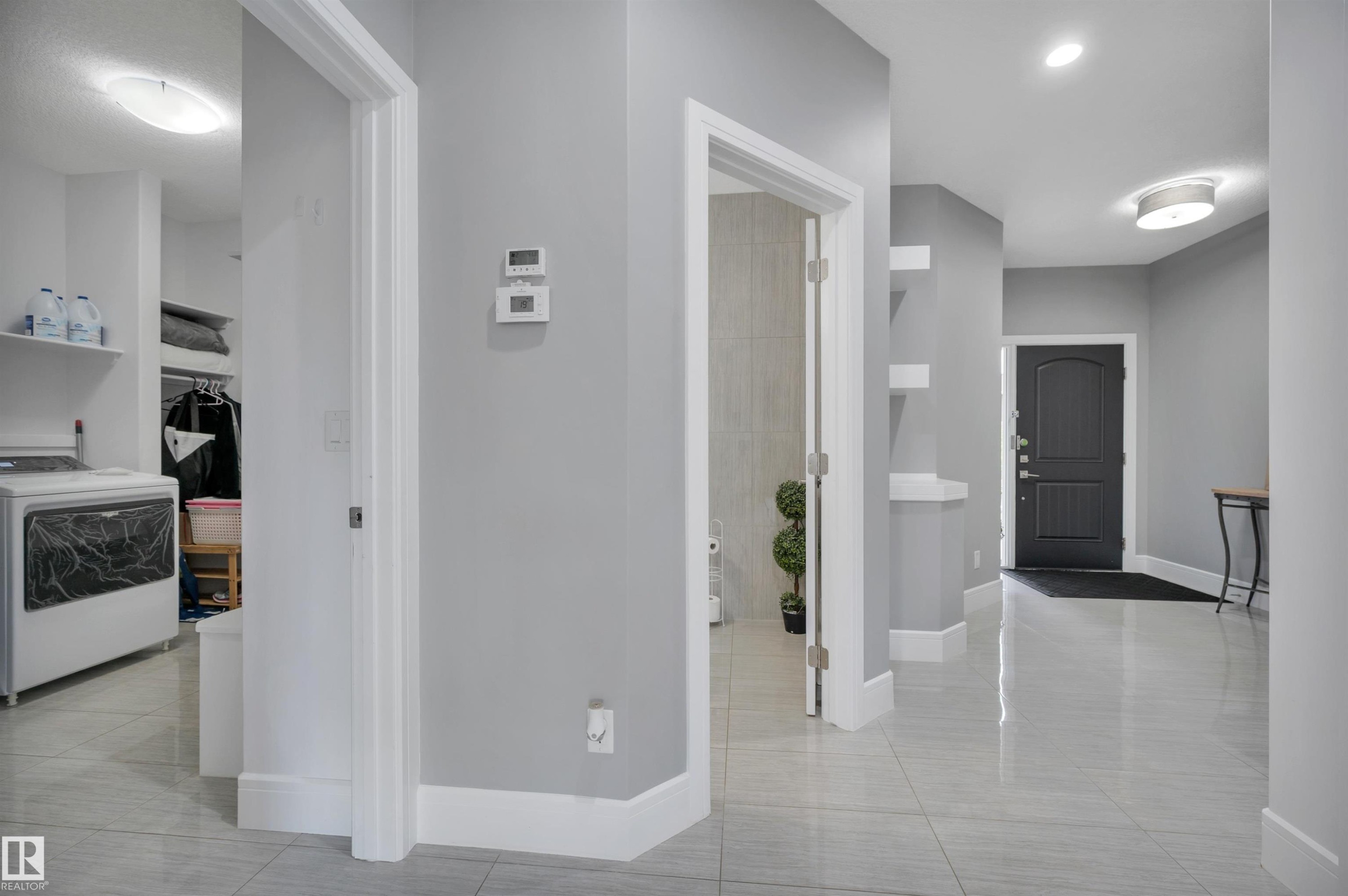 Spacious entry hallway with light gray walls, white trim, and glossy tile flooring - 3898 Robins Crescent Nw, Edmonton, AB - Indoor Photo Showing Other Room