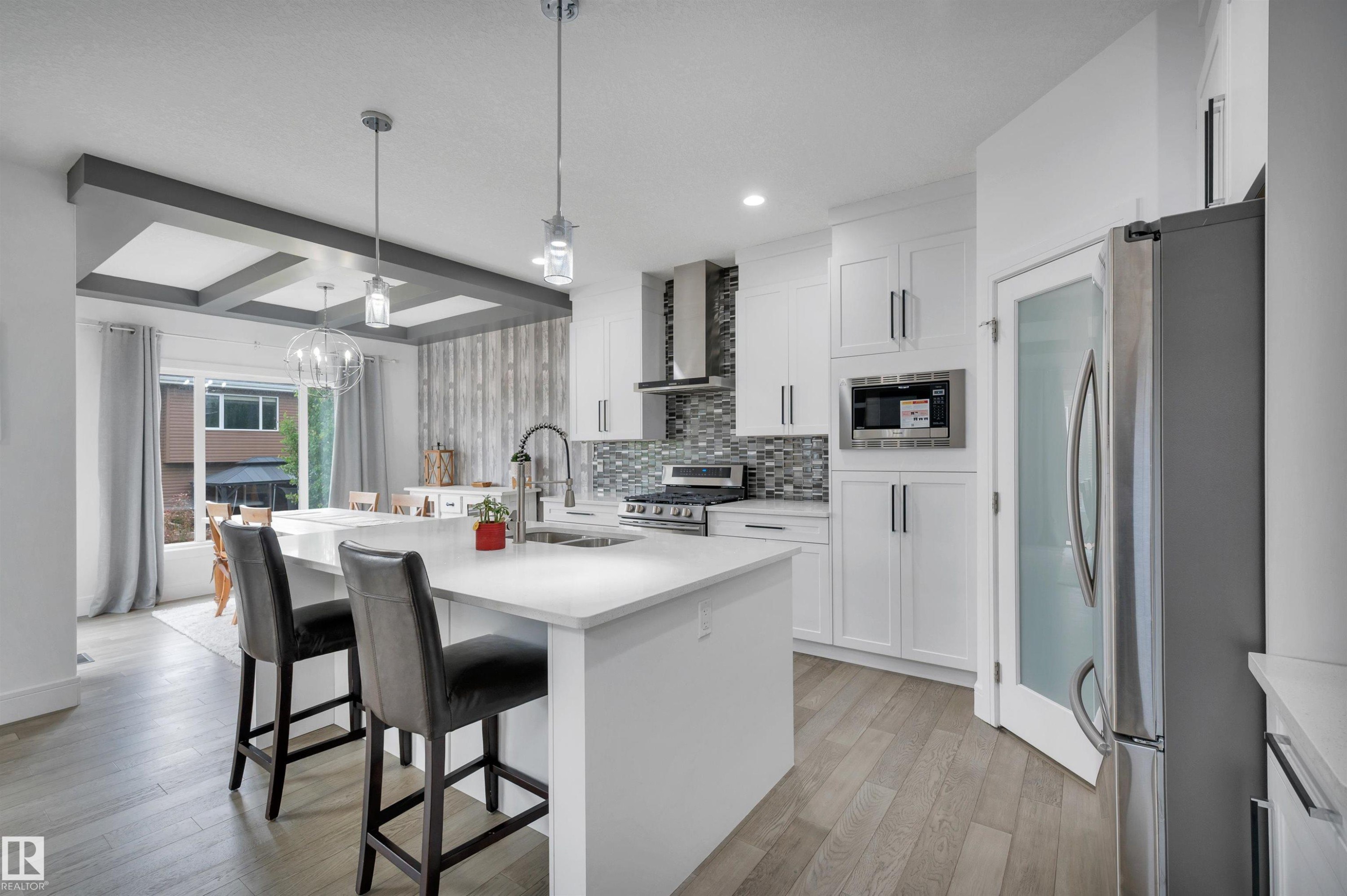Bright kitchen featuring an expansive island with a white countertop and seating - 3898 Robins Crescent Nw, Edmonton, AB - Indoor Photo Showing Kitchen With Stainless Steel Kitchen With Upgraded Kitchen