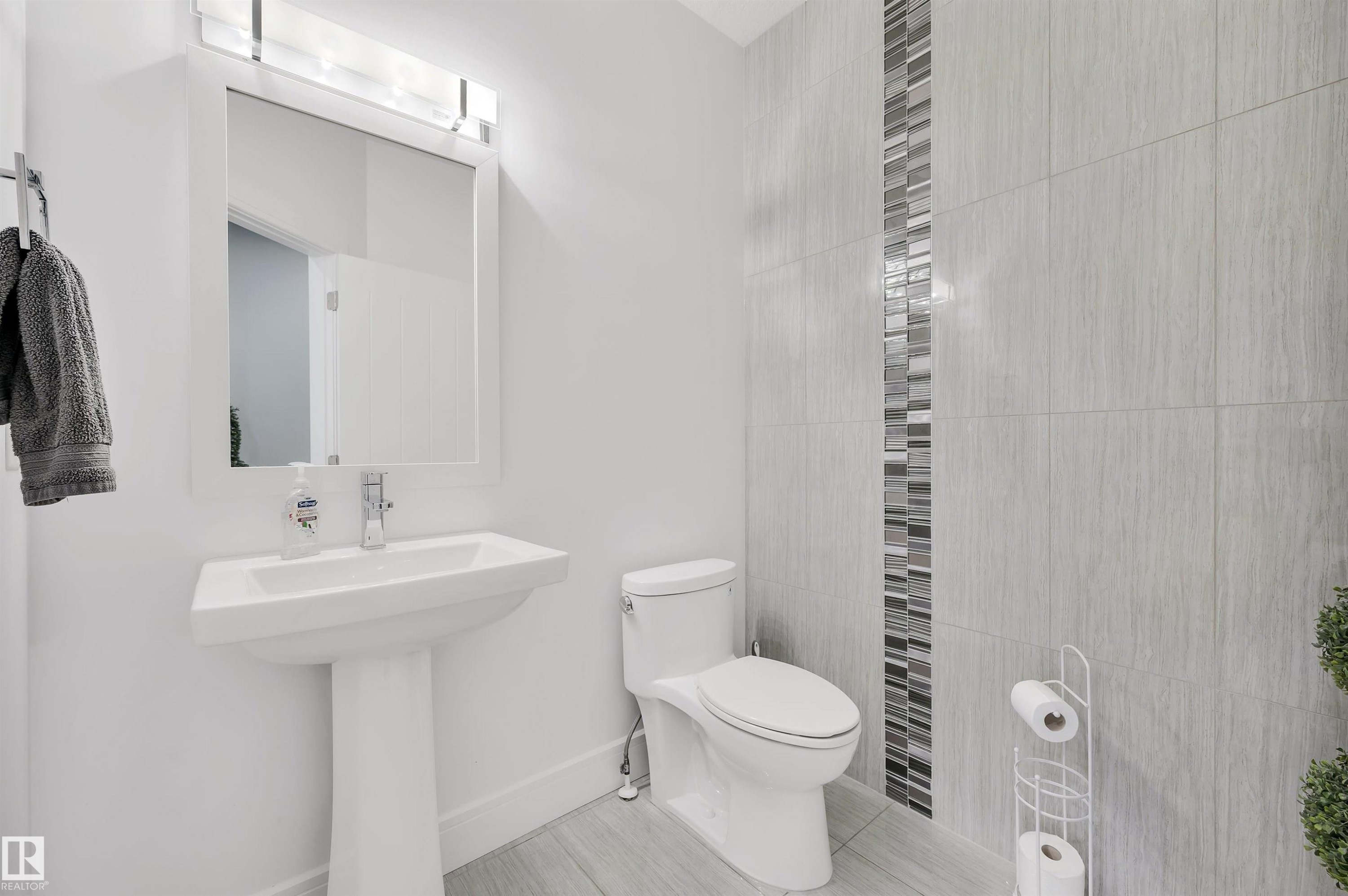 Pedestal sink with a framed mirror and overhead lighting fixture - 3898 Robins Crescent Nw, Edmonton, AB - Indoor Photo Showing Bathroom