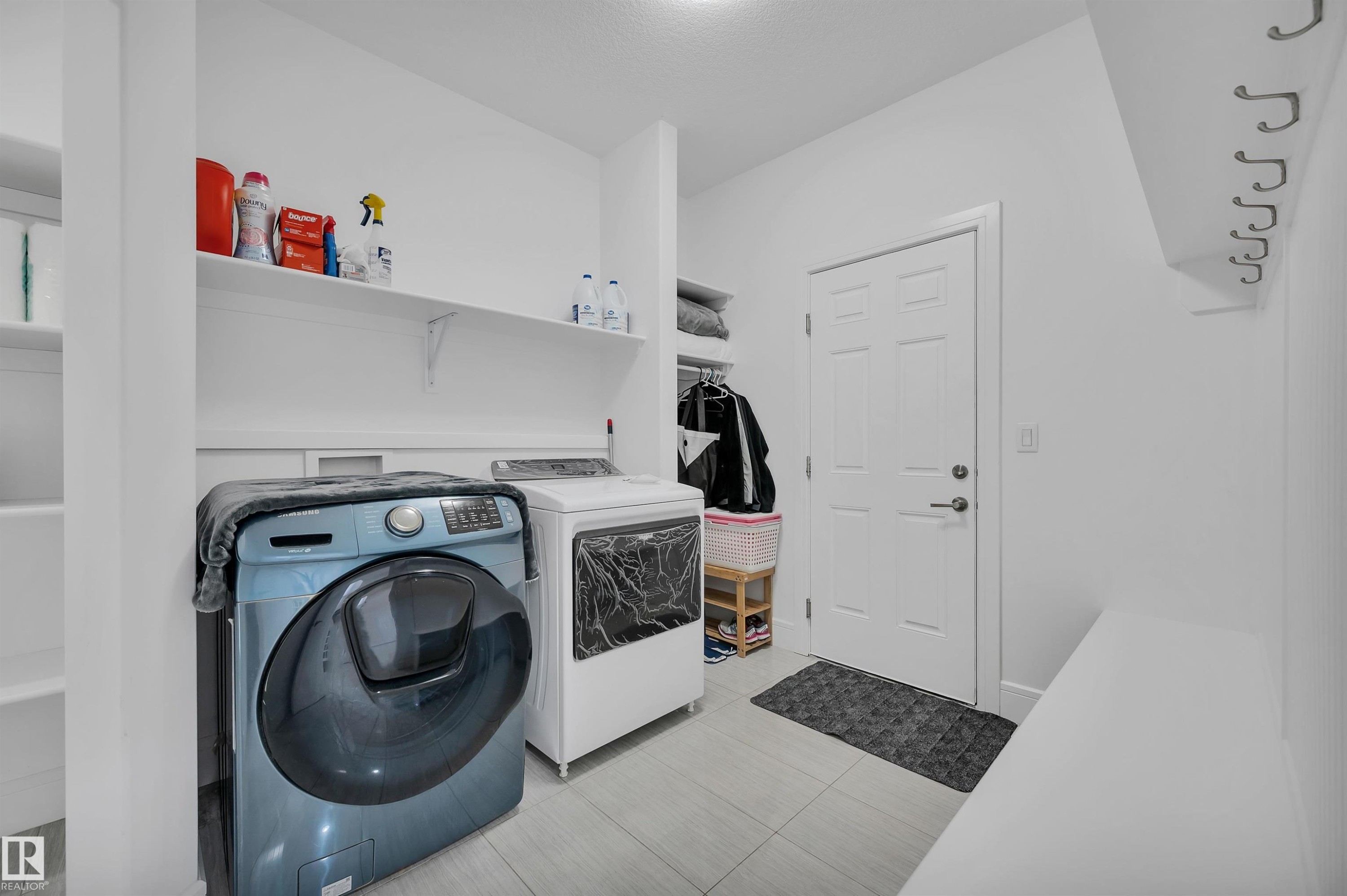 Dedicated laundry area featuring tile flooring, built-in shelving, and a wall-mounted coat rack - 3898 Robins Crescent Nw, Edmonton, AB - Indoor Photo Showing Laundry Room