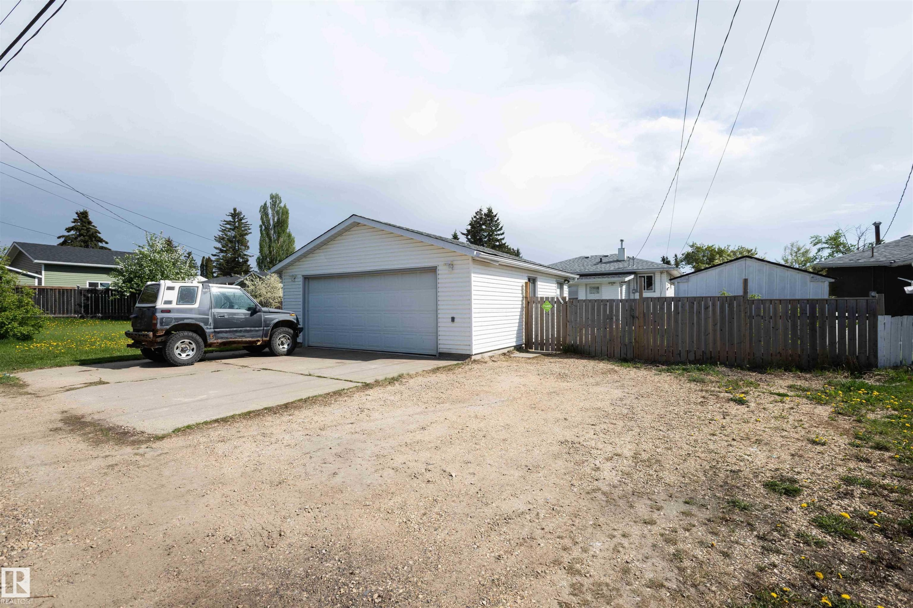 Detached garage featuring white siding, a single overhead door, and a concrete driveway pad - 4414 54 Avenue, Barrhead, AB - Outdoor