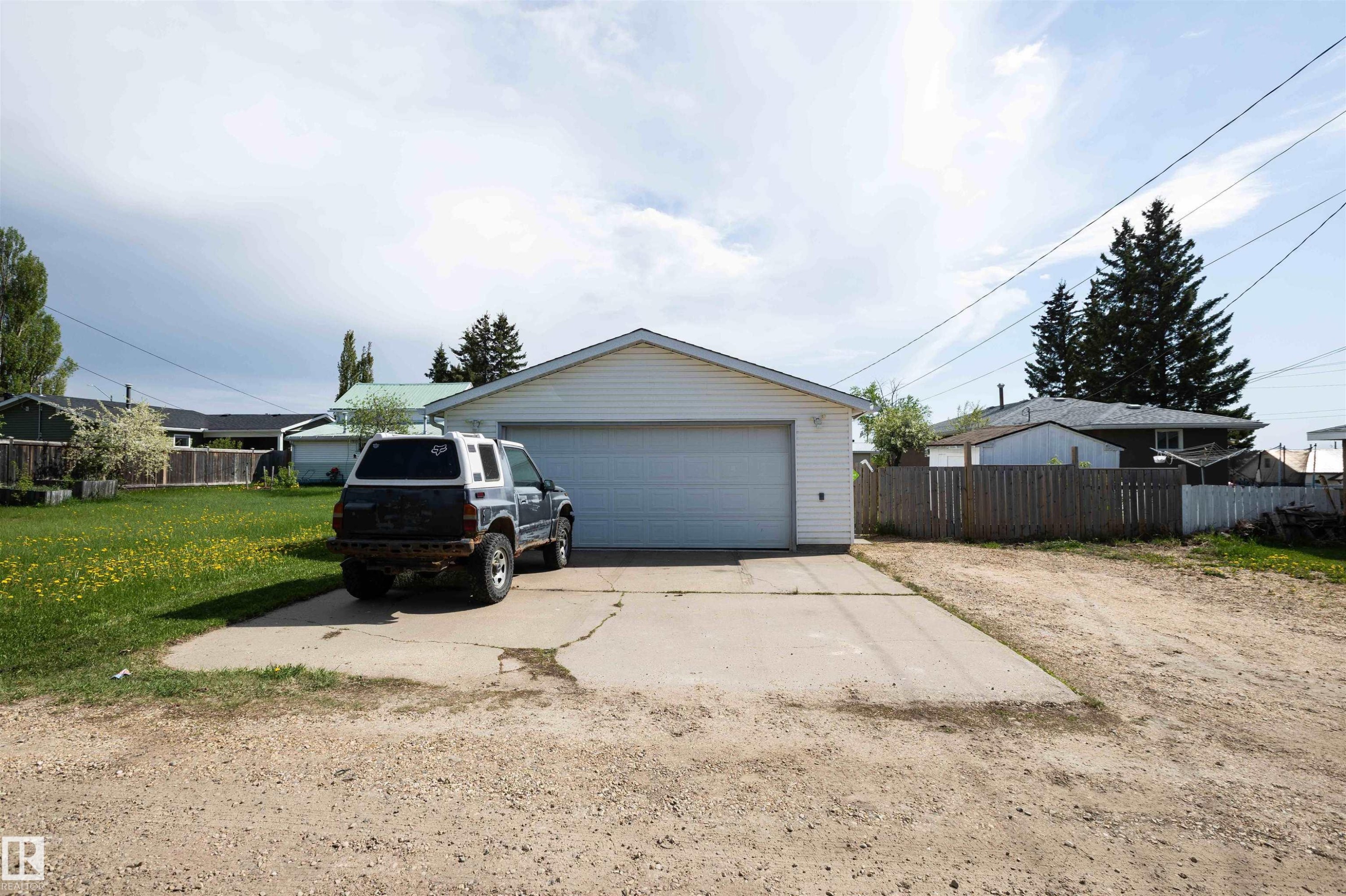 Detached garage with white siding, a single overhead door, and a concrete driveway - 4414 54 Avenue, Barrhead, AB - Outdoor
